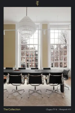 Vergaderruimte met moderne stoelen en een grote kroonluchter aan het plafond, met uitzicht op grachtenpanden aan de Herengracht.