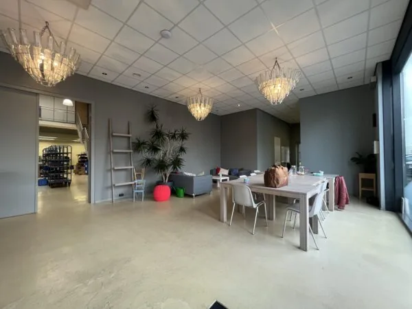 Een moderne ruimte met een houten tafel en stoelen, omgeven door planten en hangende lampen.