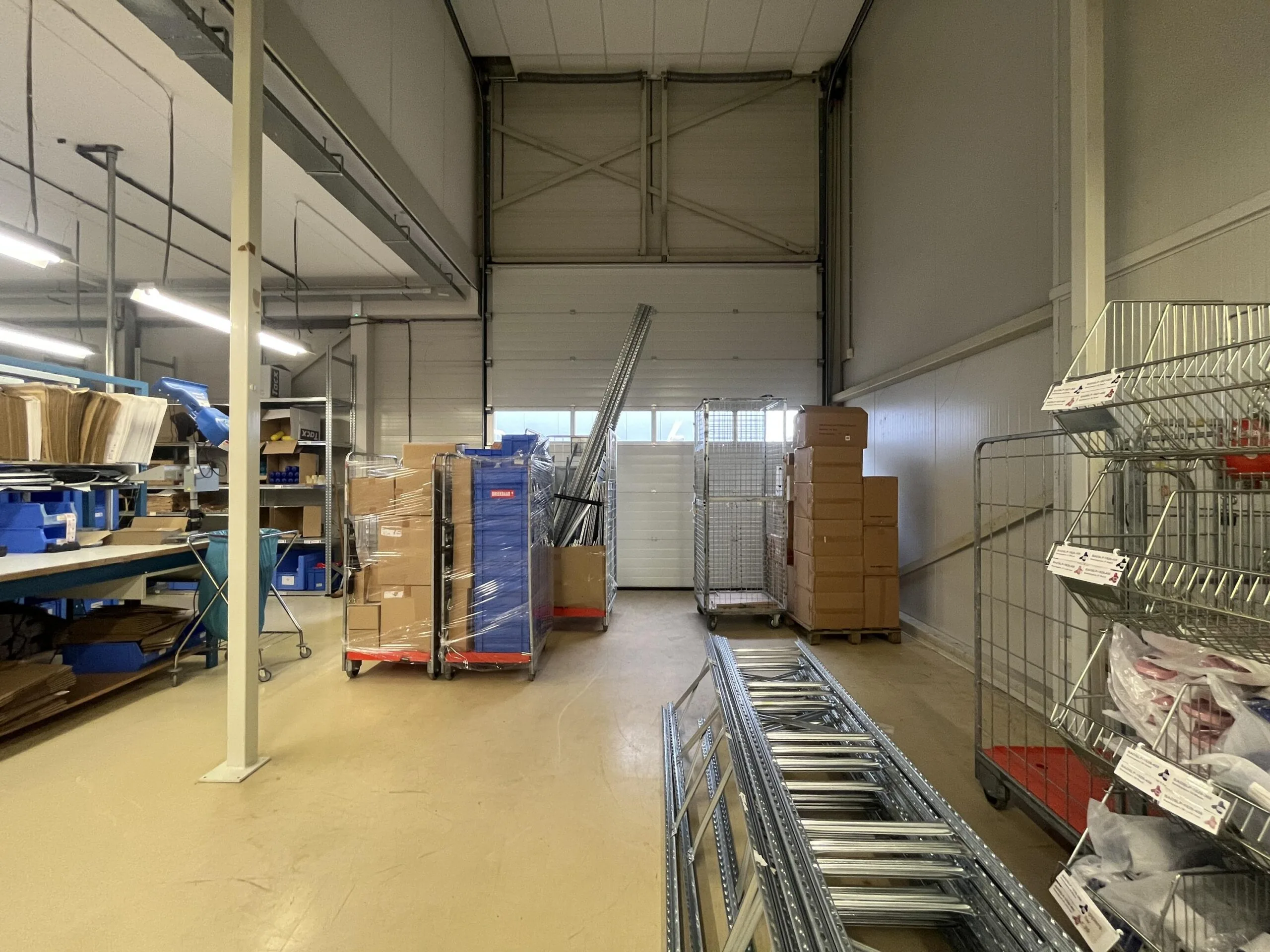 Een magazijn gevuld met kartonnen dozen, metalen rekken en andere opbergmaterialen.