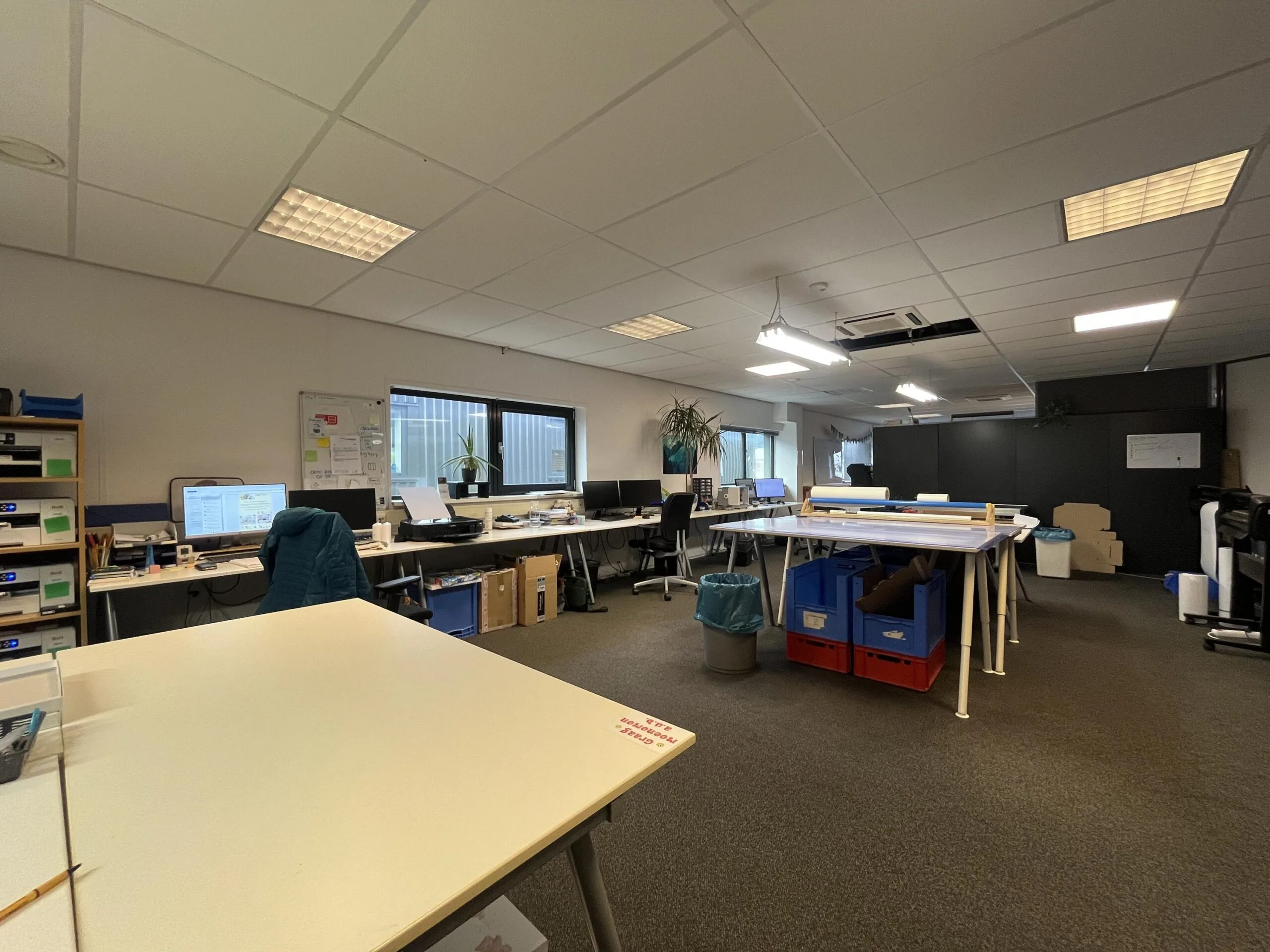 Een modern kantoor met bureaus, computers en diverse kantoorartikelen.