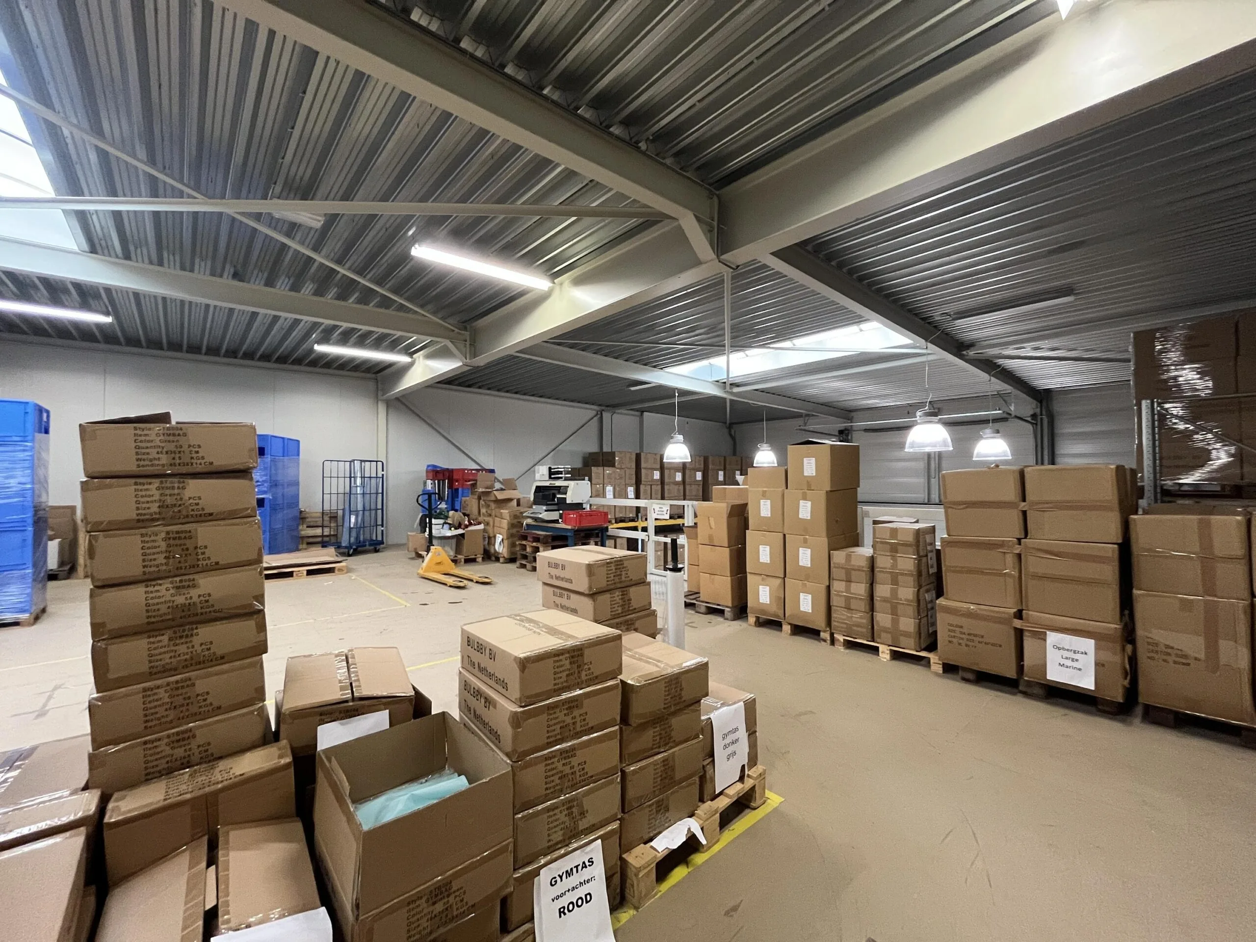 Een opslagruimte met stapels bruine kartonnen dozen op pallets.