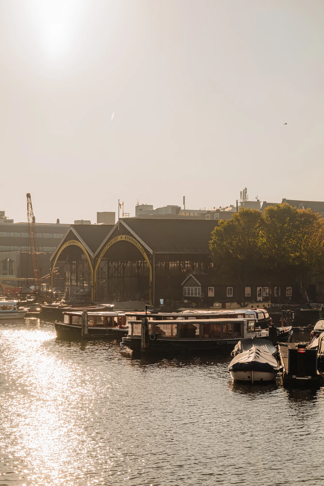 Zicht op boten en een historische scheepswerf aan de Hoogte Kadijk bij zonsopgang.
