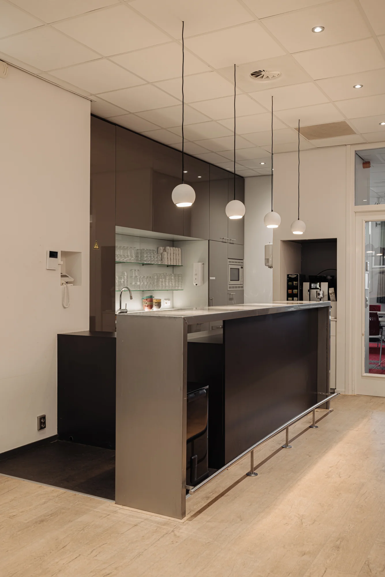 Moderne keuken met hangende lampen, een bar, en opbergkasten in een kantooromgeving.
