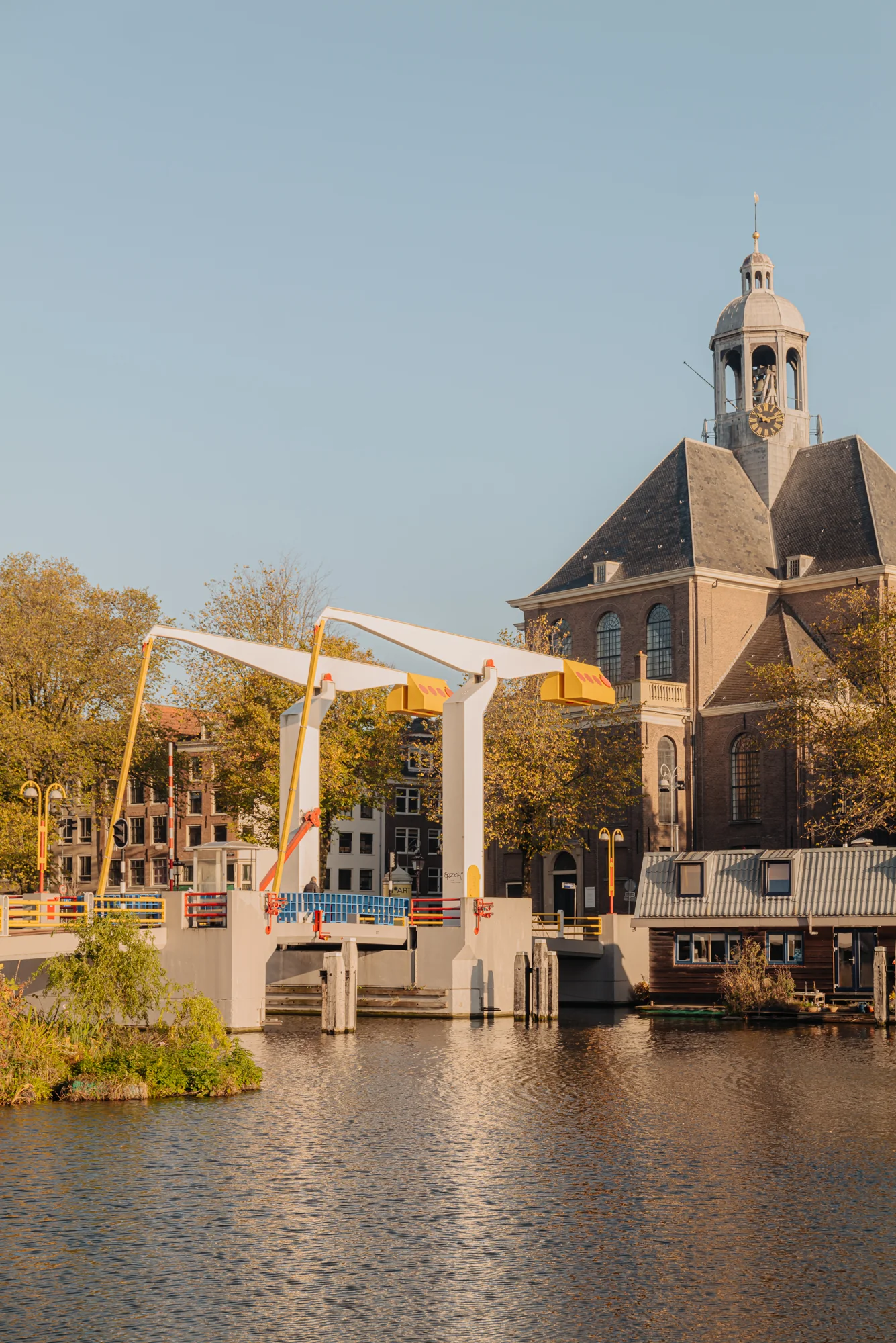 Een ophaalbrug bij de Hoogte Kadijk, met een historische kerk en huisjes langs het water.