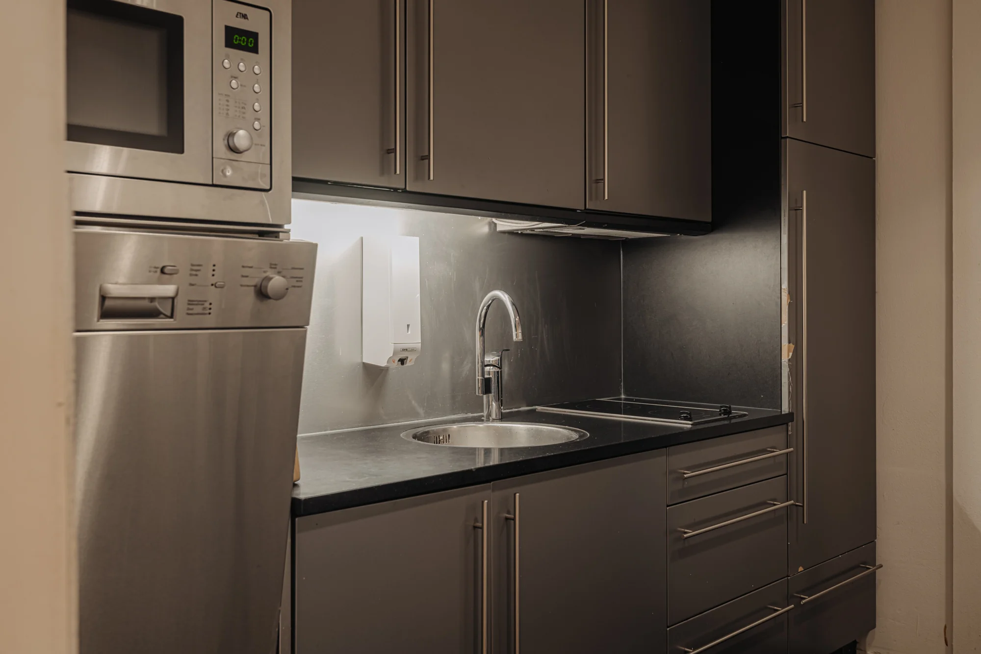 Moderne keuken met roestvrijstalen apparatuur en een ronde gootsteen.