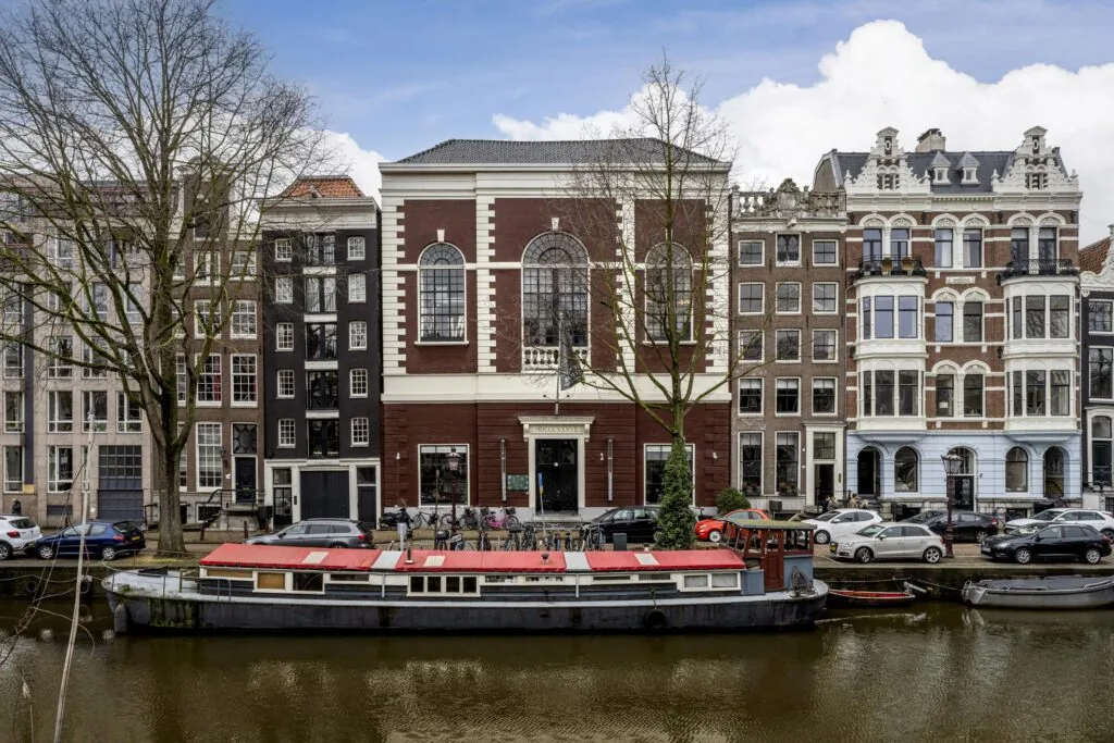 Een grachtenpand aan de Keizersgracht met een boot in de gracht in Amsterdam.