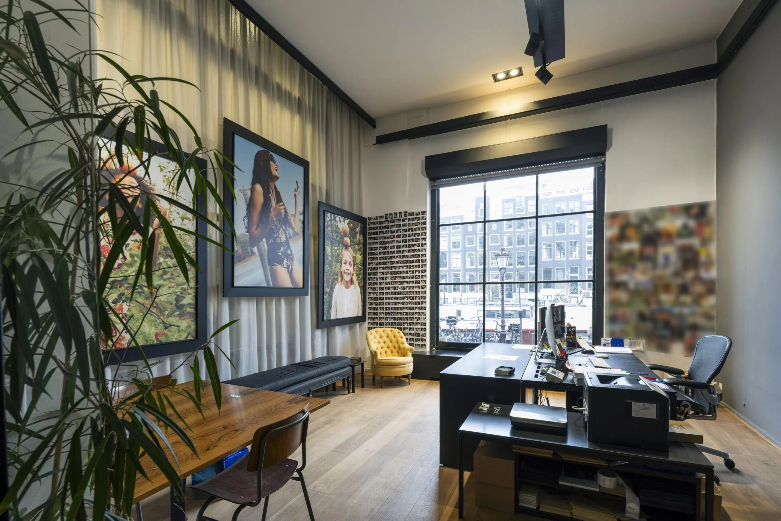 Een modern kantoor aan de Keizersgracht met grote foto's aan de muur en uitzicht op de grachten.