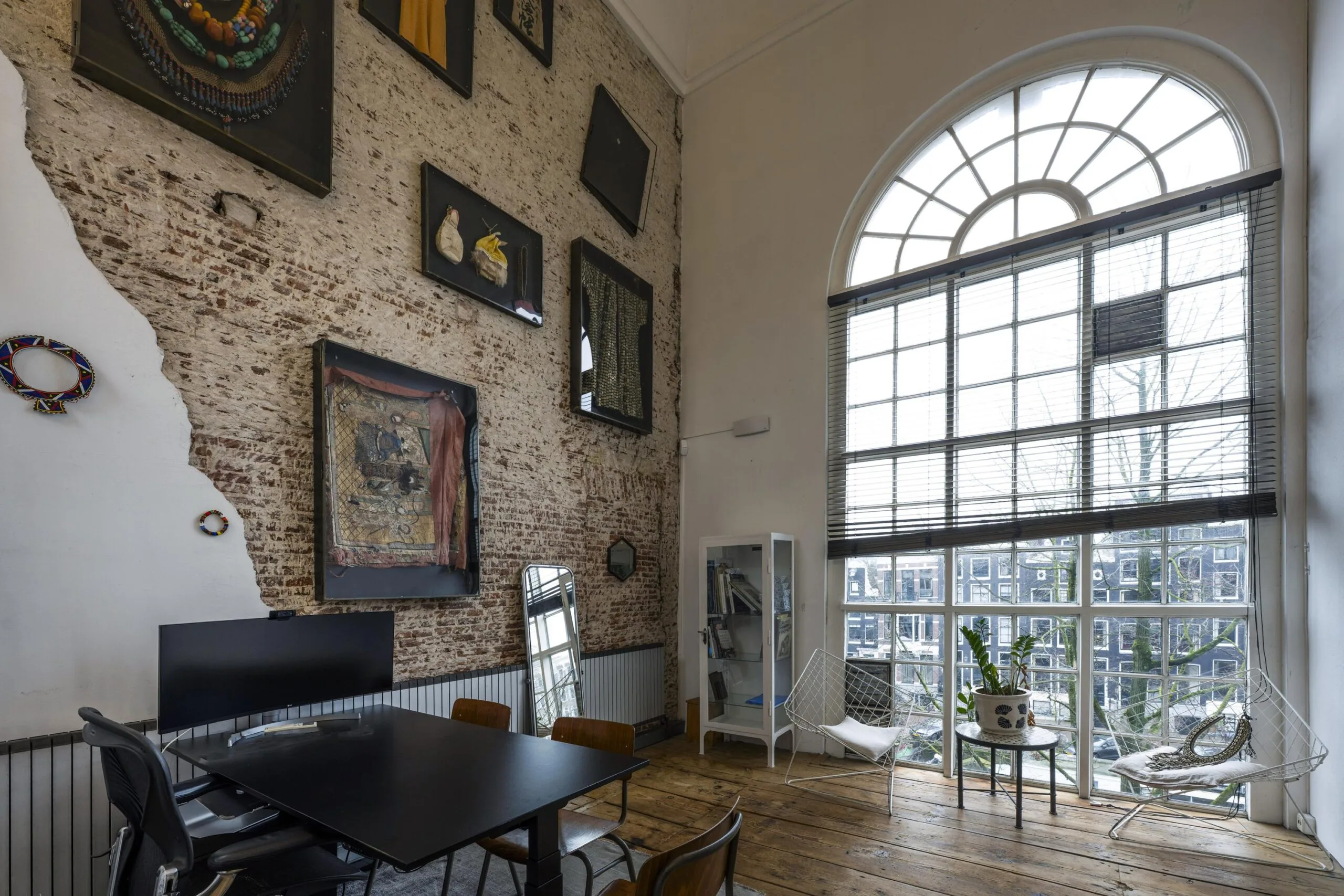 Een stijlvolle vergaderruimte aan de Keizersgracht met bakstenen muur, grote ramen en moderne kunst aan de muur.
