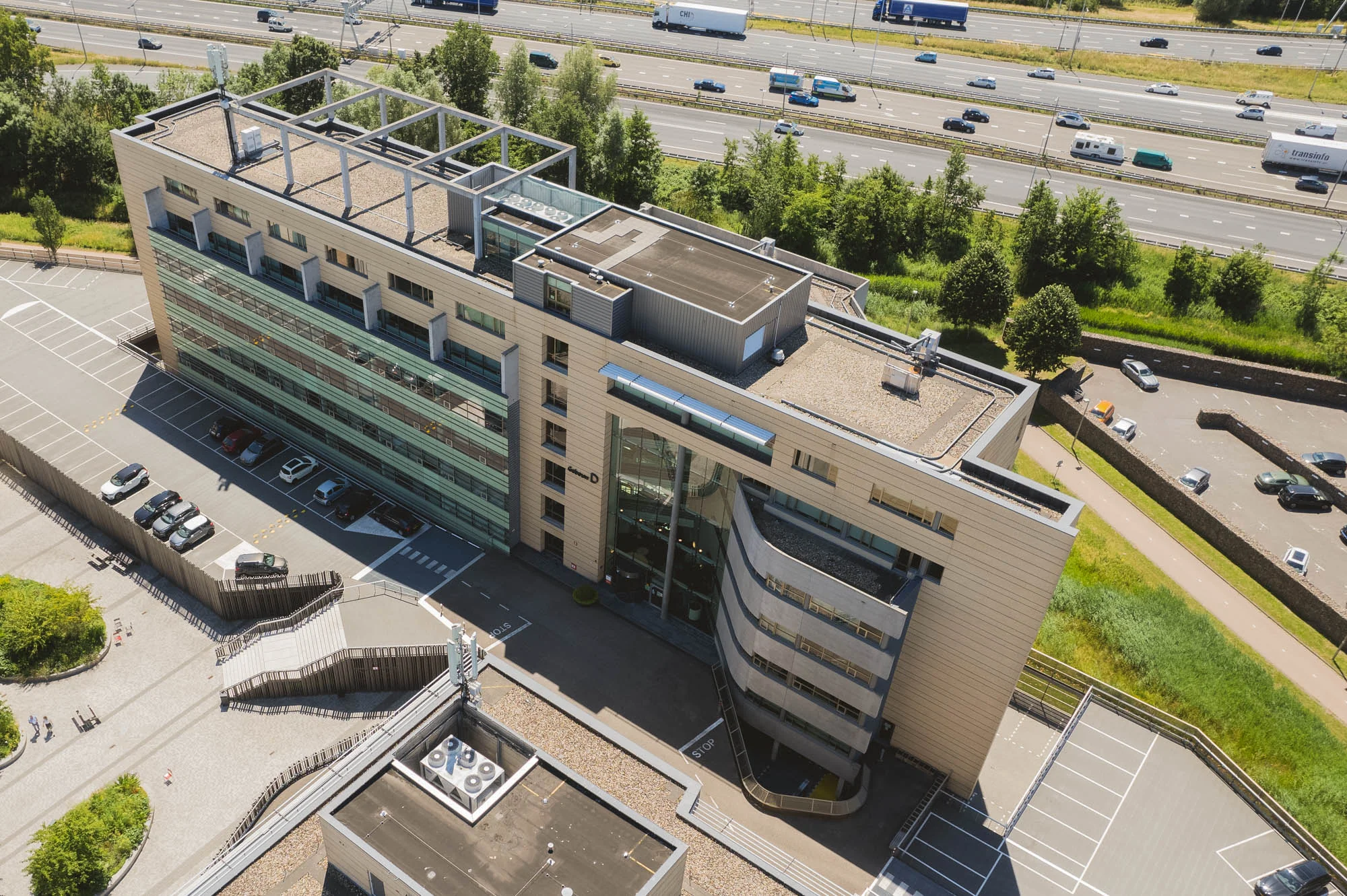 Luchtfoto van een modern kantoorgebouw aan de Papendorpseweg nabij een snelweg met voorbijrijdend verkeer.