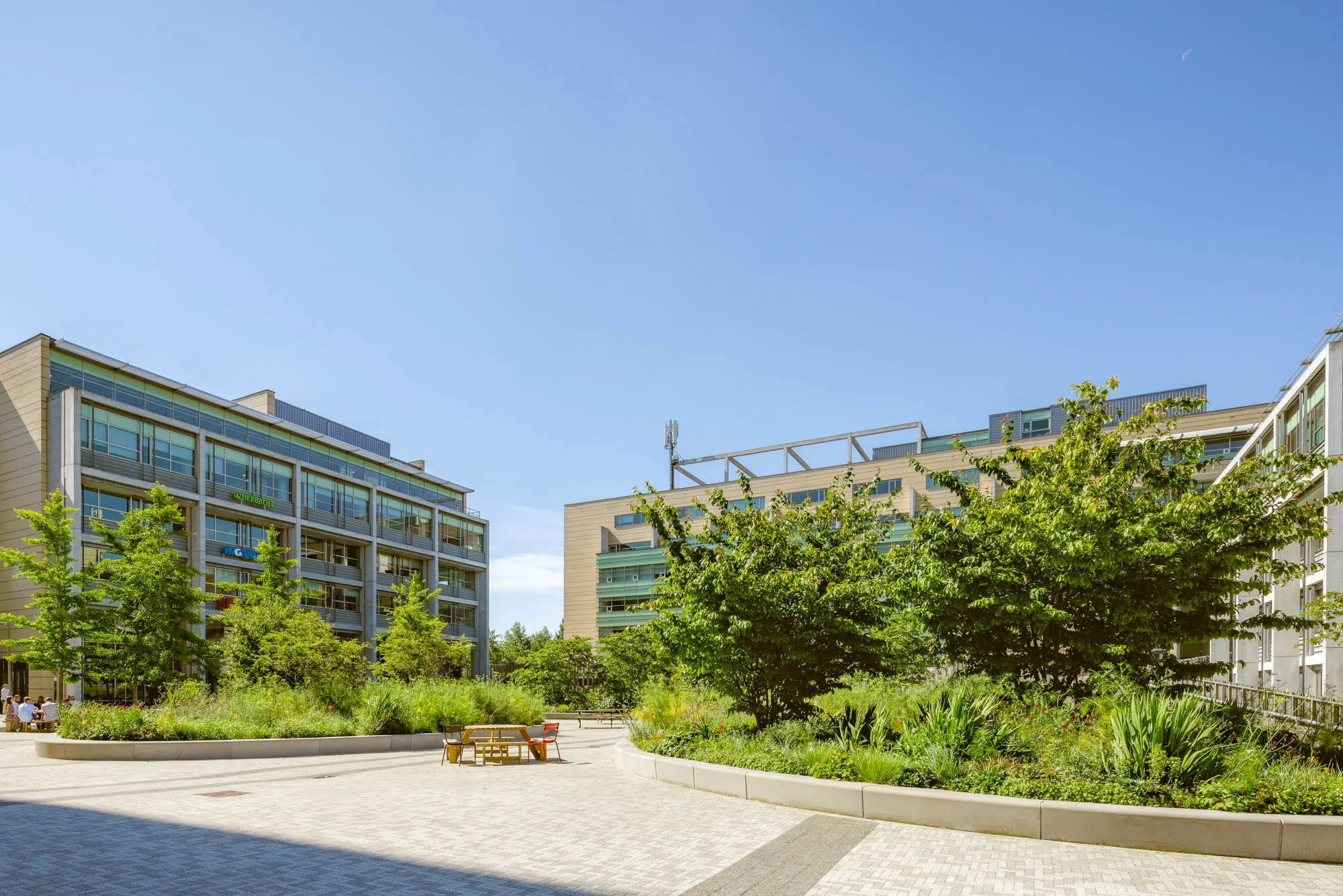 Modern kantoorgebouw aan de Papendorpseweg met omringende groene tuin en bankjes onder een blauwe hemel.