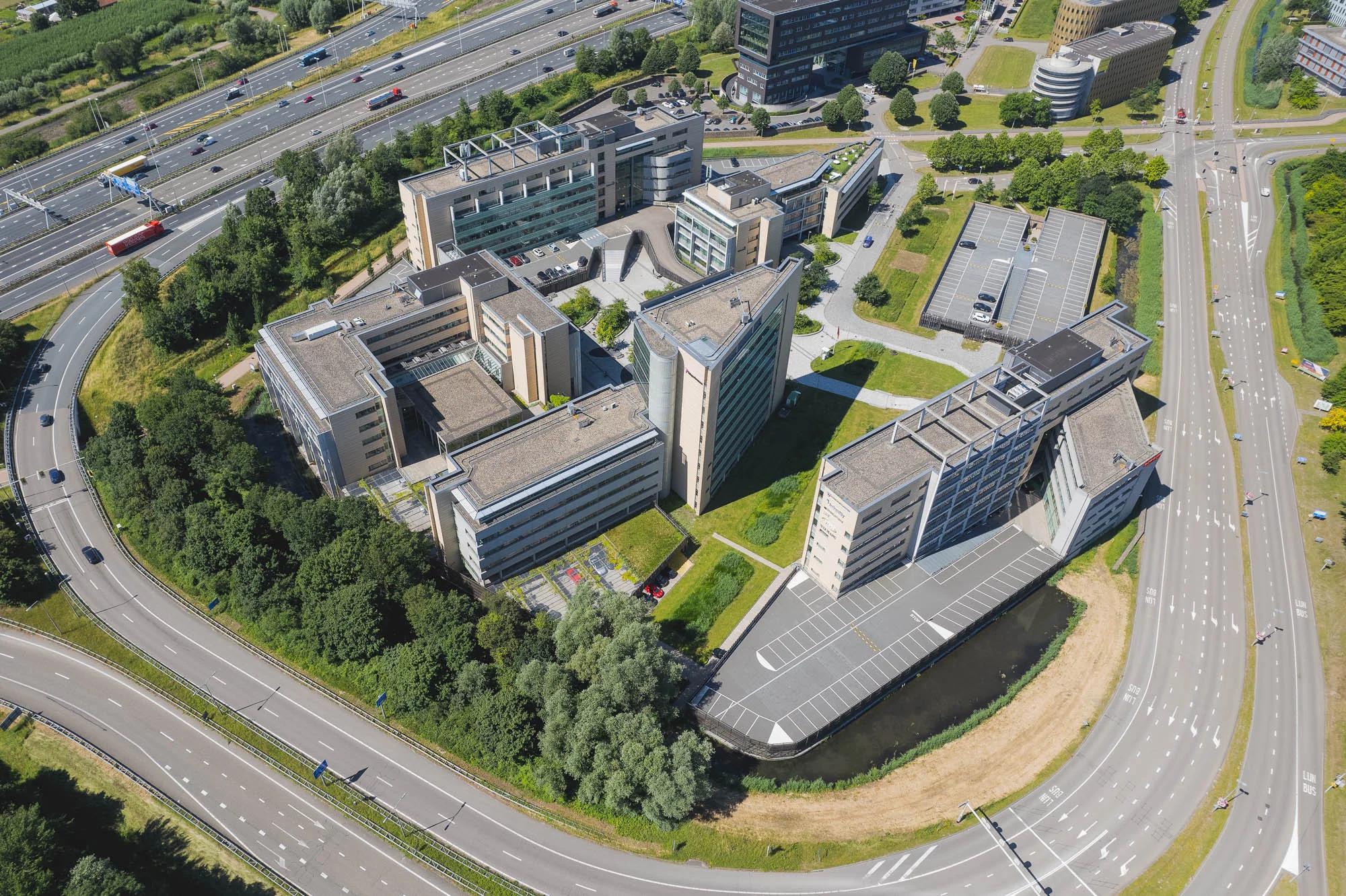 Luchtfoto van een groot kantoorgebouwcomplex aan de Papendorpseweg, omringd door wegen en groen.