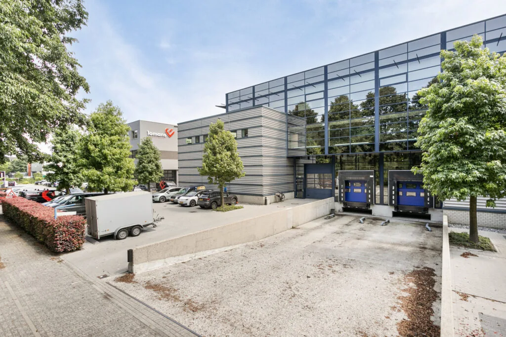 Een modern kantoorgebouw met glazen gevel en laadperrons op een bedrijventerrein.