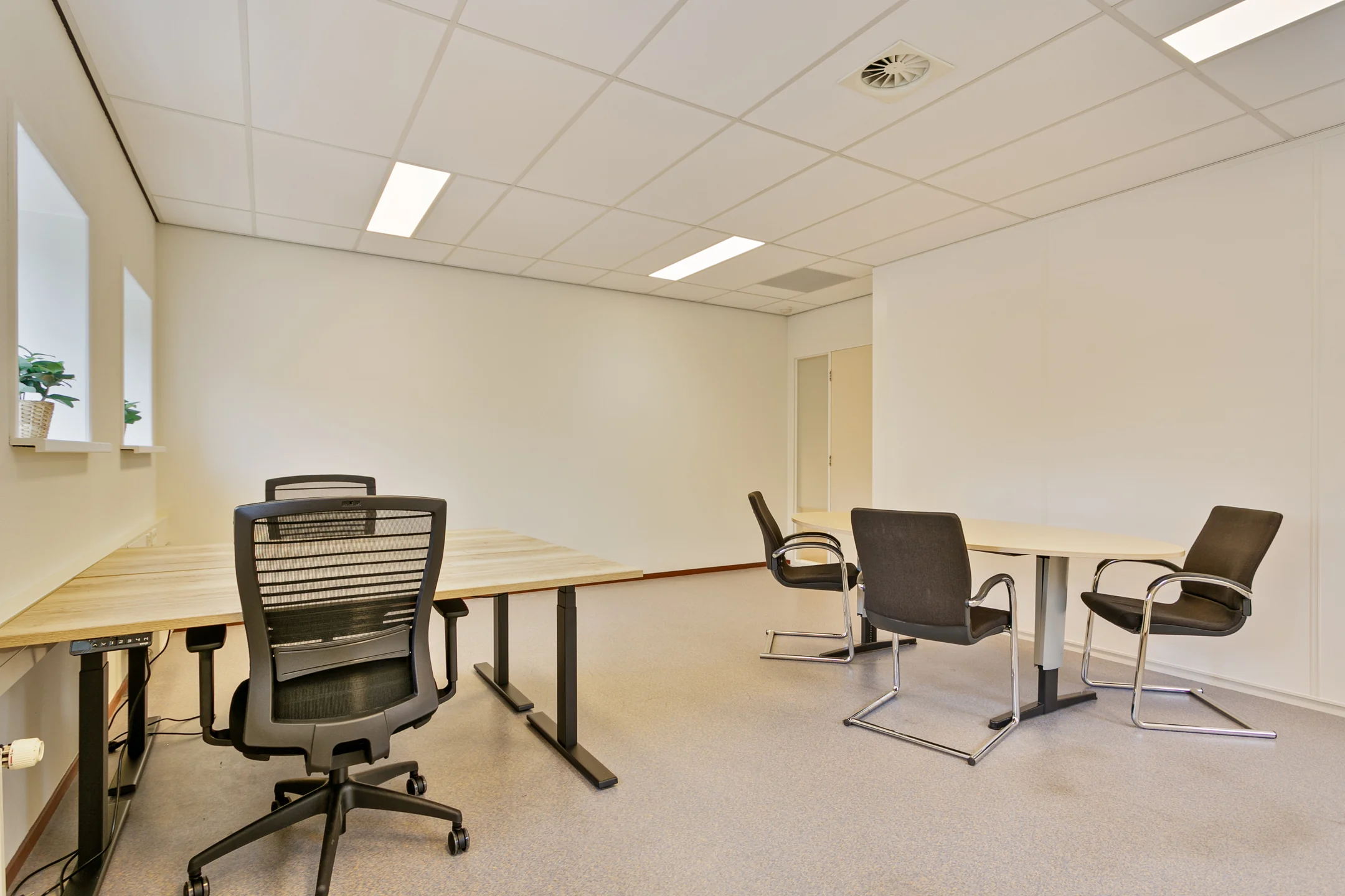 Een lege kantoorruimte met bureaus en meerdere stoelen.