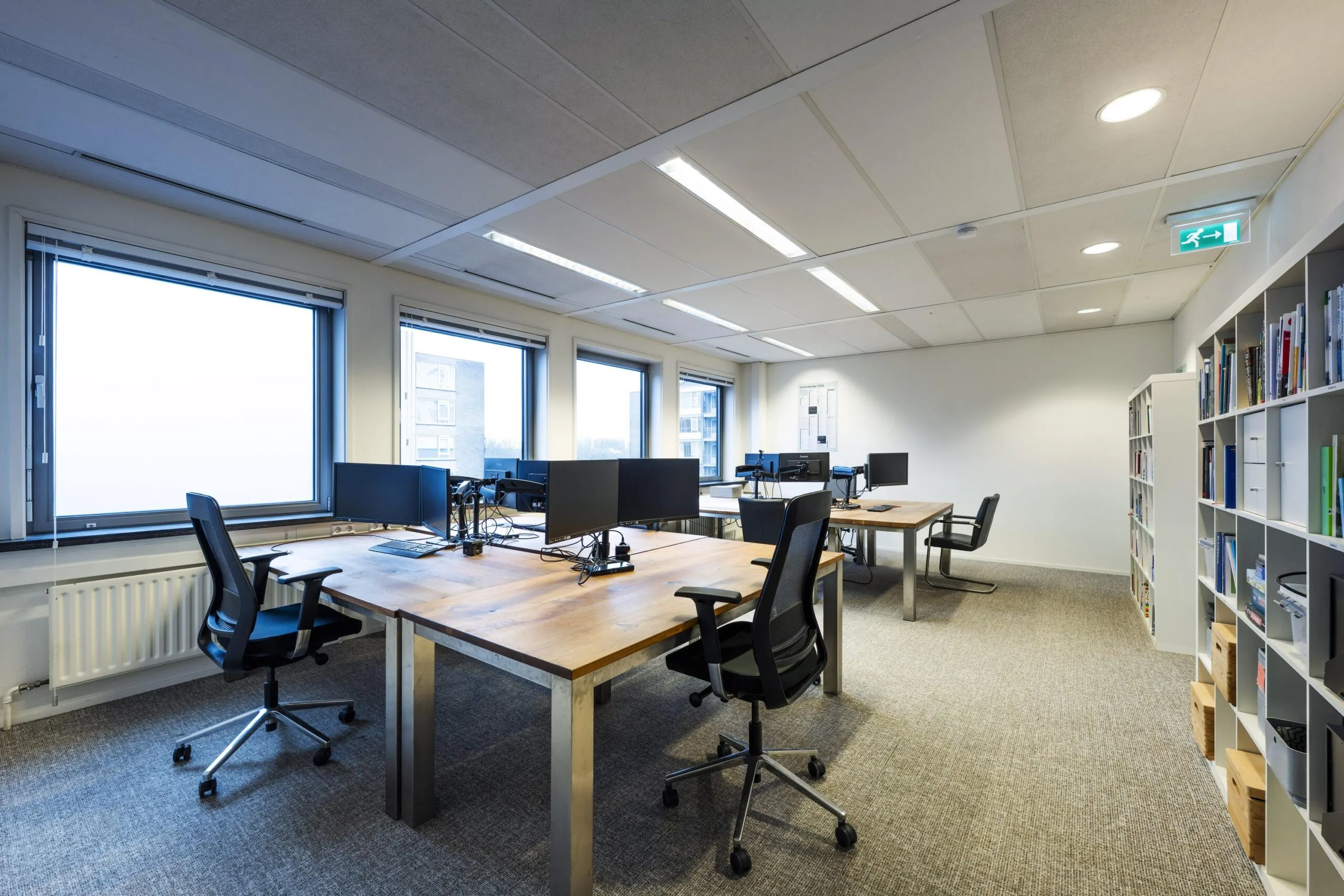 Een modern kantoorpand met houten bureaus, zwarte bureaustoelen, en grote ramen aan de Rembrandtweg.