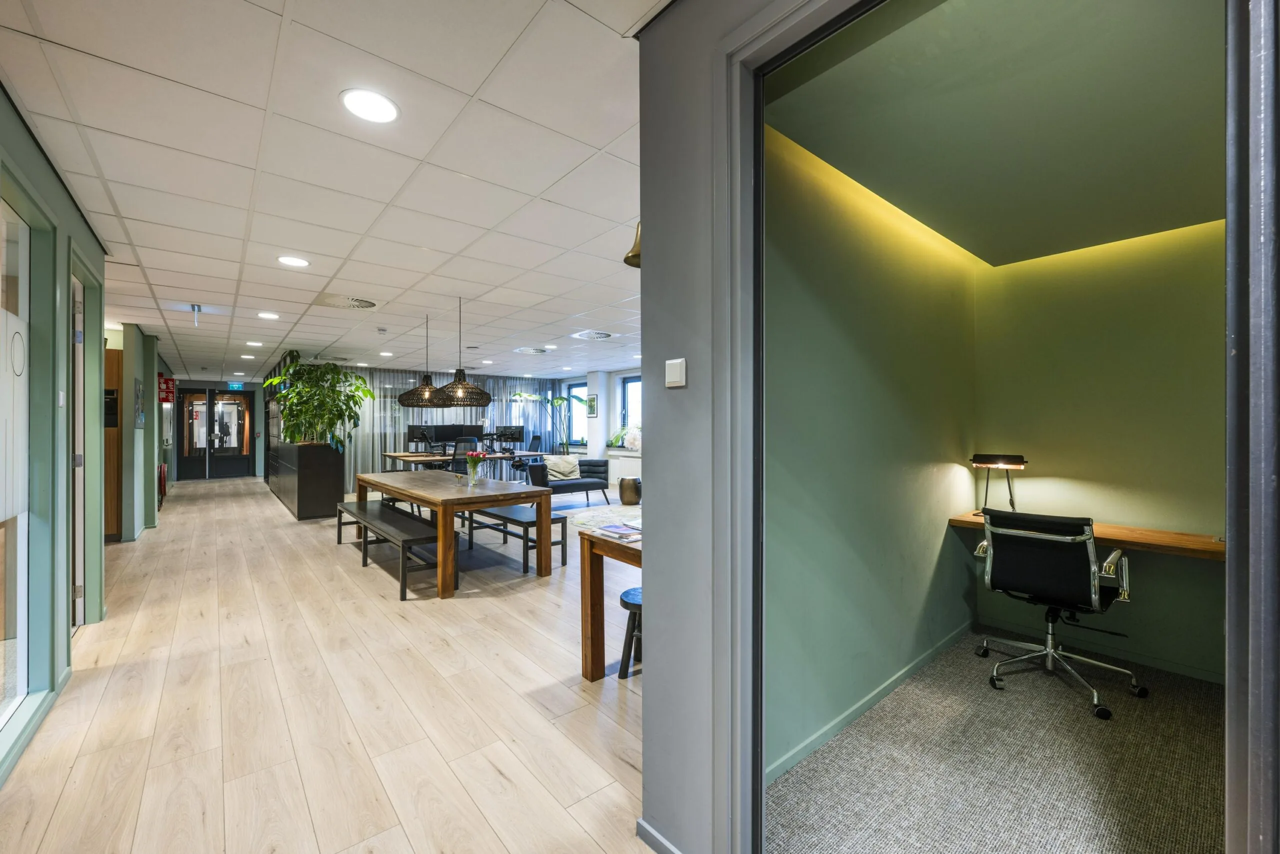 Een moderne kantoorruimte met houten vloeren en een aparte werkruimte met een bureau en stoel.
