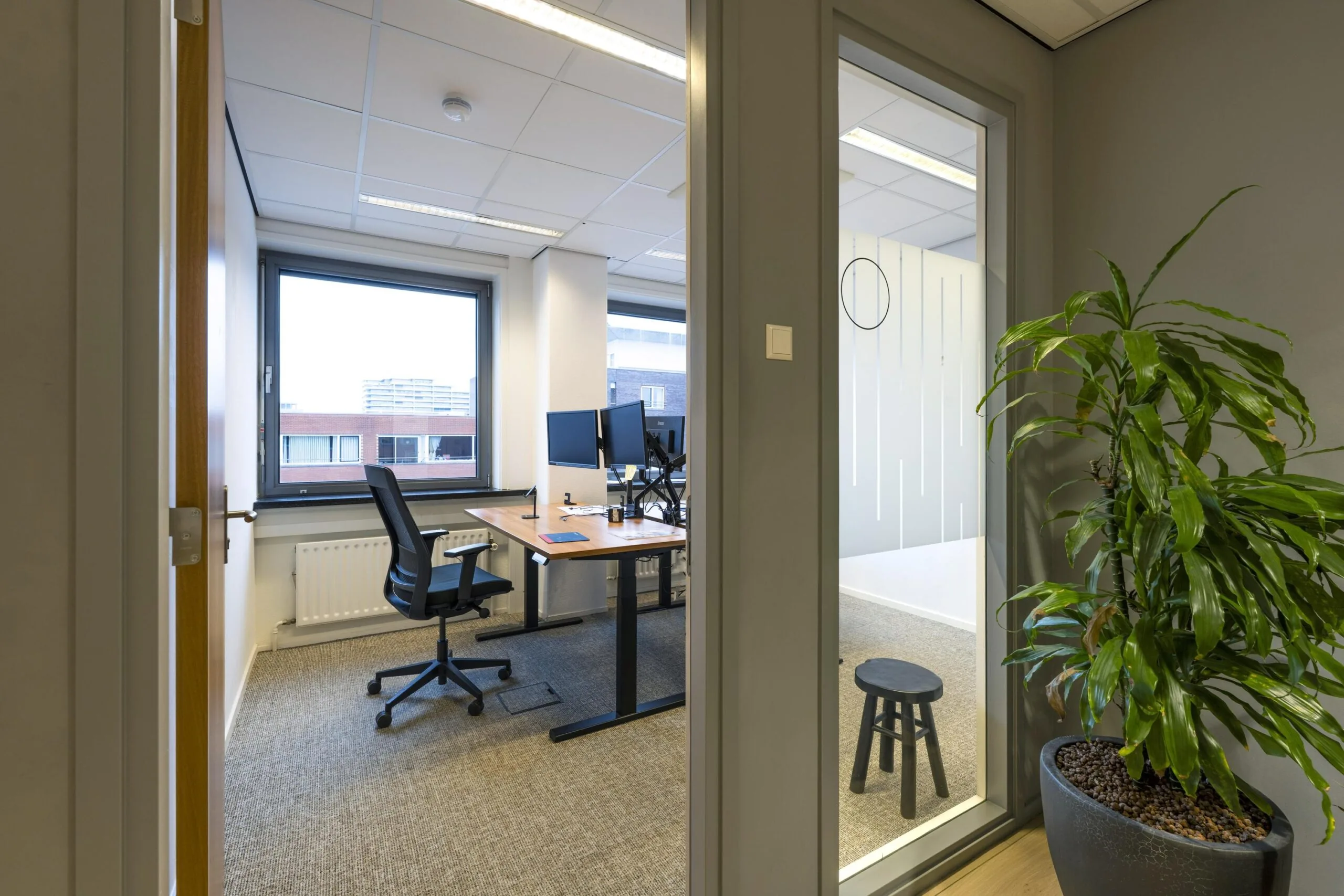 Een moderne kantoorruimte met een bureau, een bureaustoel, en een groot raam, aan de Rembrandtweg.