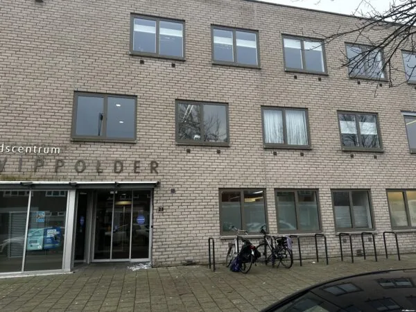 Vooraanzicht van een gebouw met de tekst "Gezondheidscentrum Wippolder" boven de ingang, met fietsen ervoor geparkeerd.