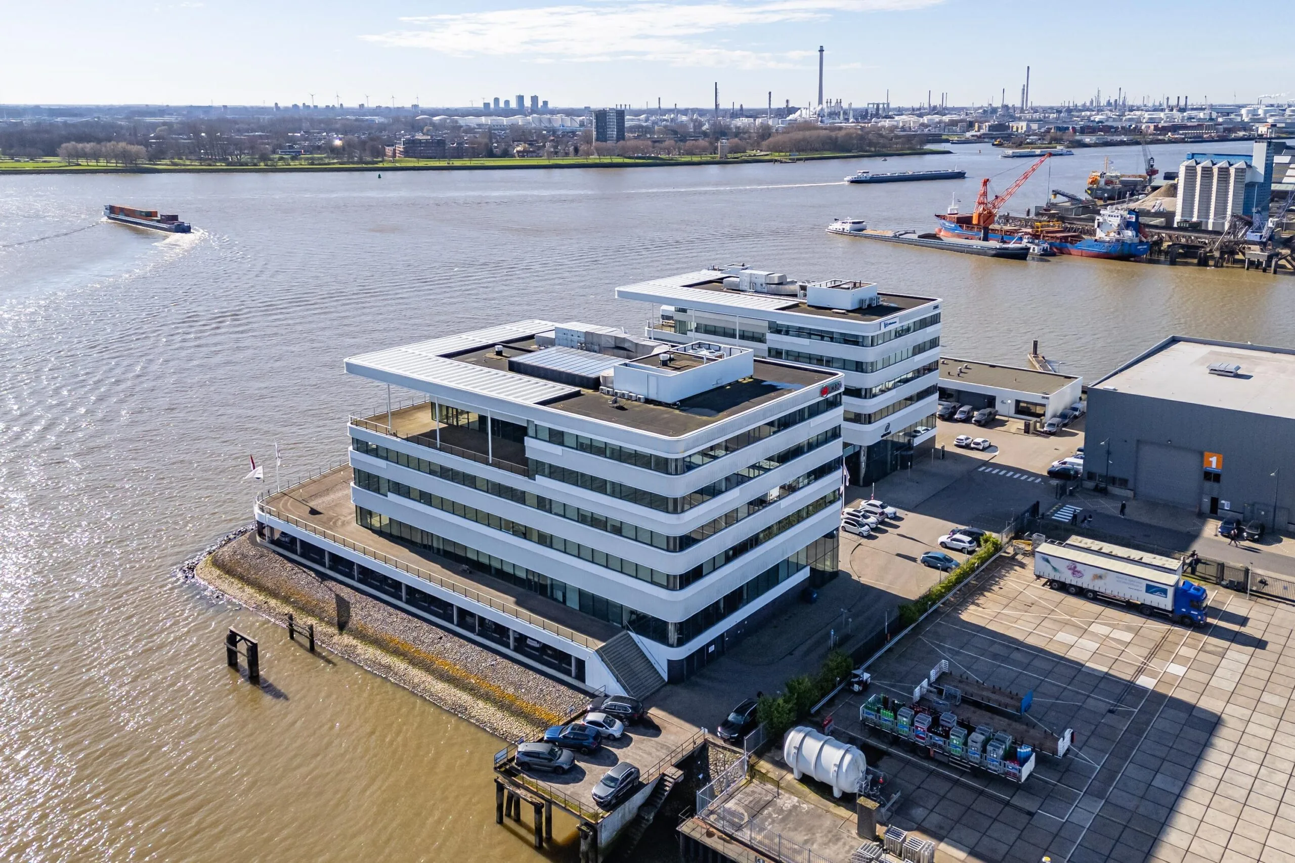 Luchtfoto van moderne kantoorgebouwen aan de waterkant van Havenstraat met schepen op de rivier.