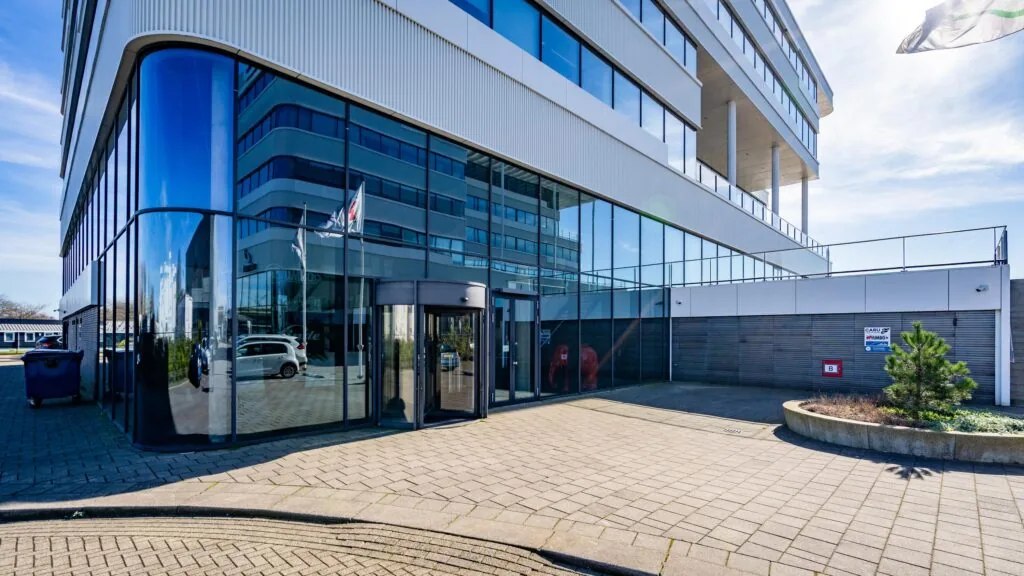 Moderne kantoorgebouw aan de Havenstraat met glazen entree en vlaggenmast op een zonnige dag.