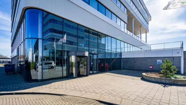 Moderne kantoorgebouw aan de Havenstraat met glazen entree en vlaggenmast op een zonnige dag.
