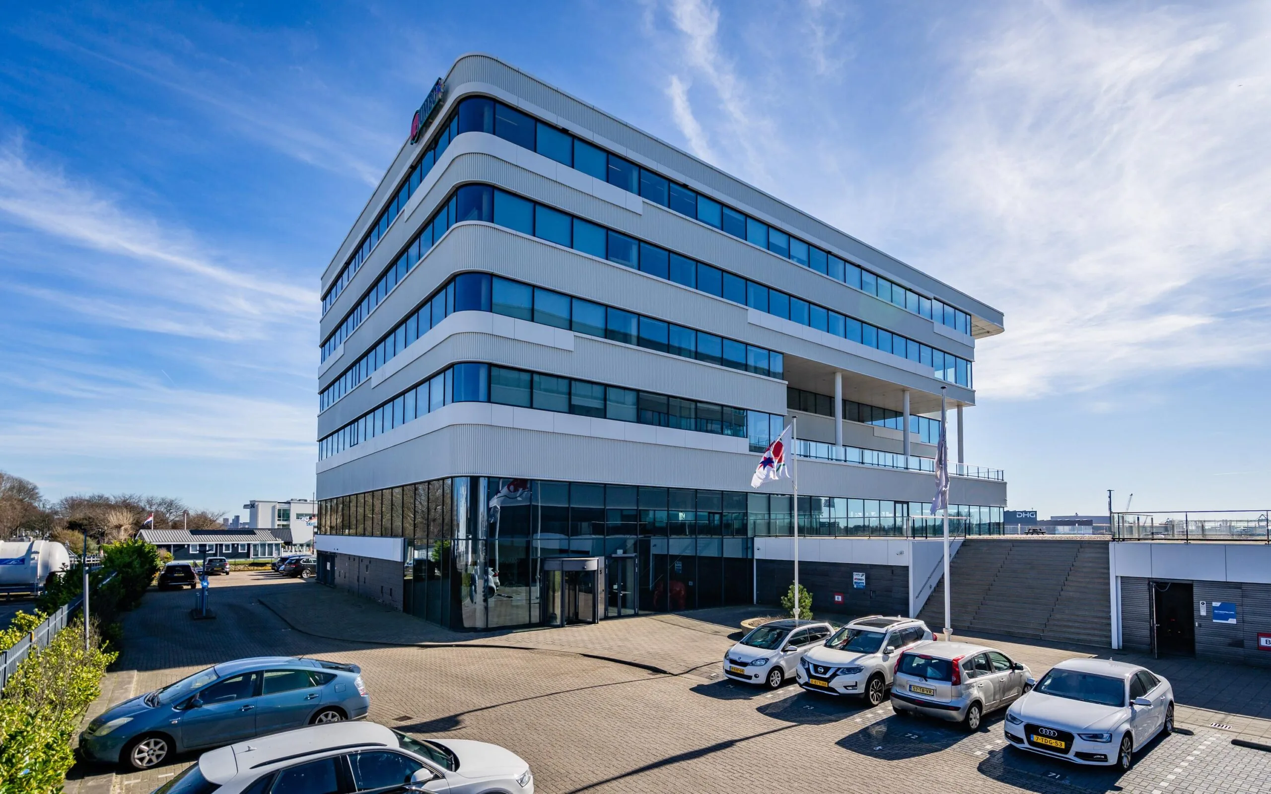 Modern kantoorgebouw aan de Havenstraat met auto's geparkeerd op de voorgrond.