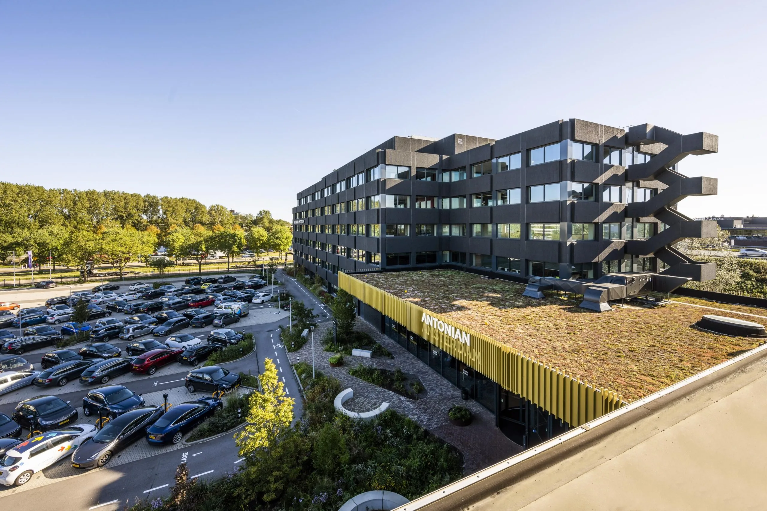 Een modern gebouw met een groen dak en een volle parkeerplaats op Spaklerweg.