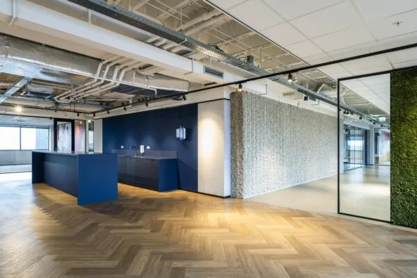 Moderne bedrijfsruimte met een blauwe balie, houten vloer en groene wand op Spaklerweg.