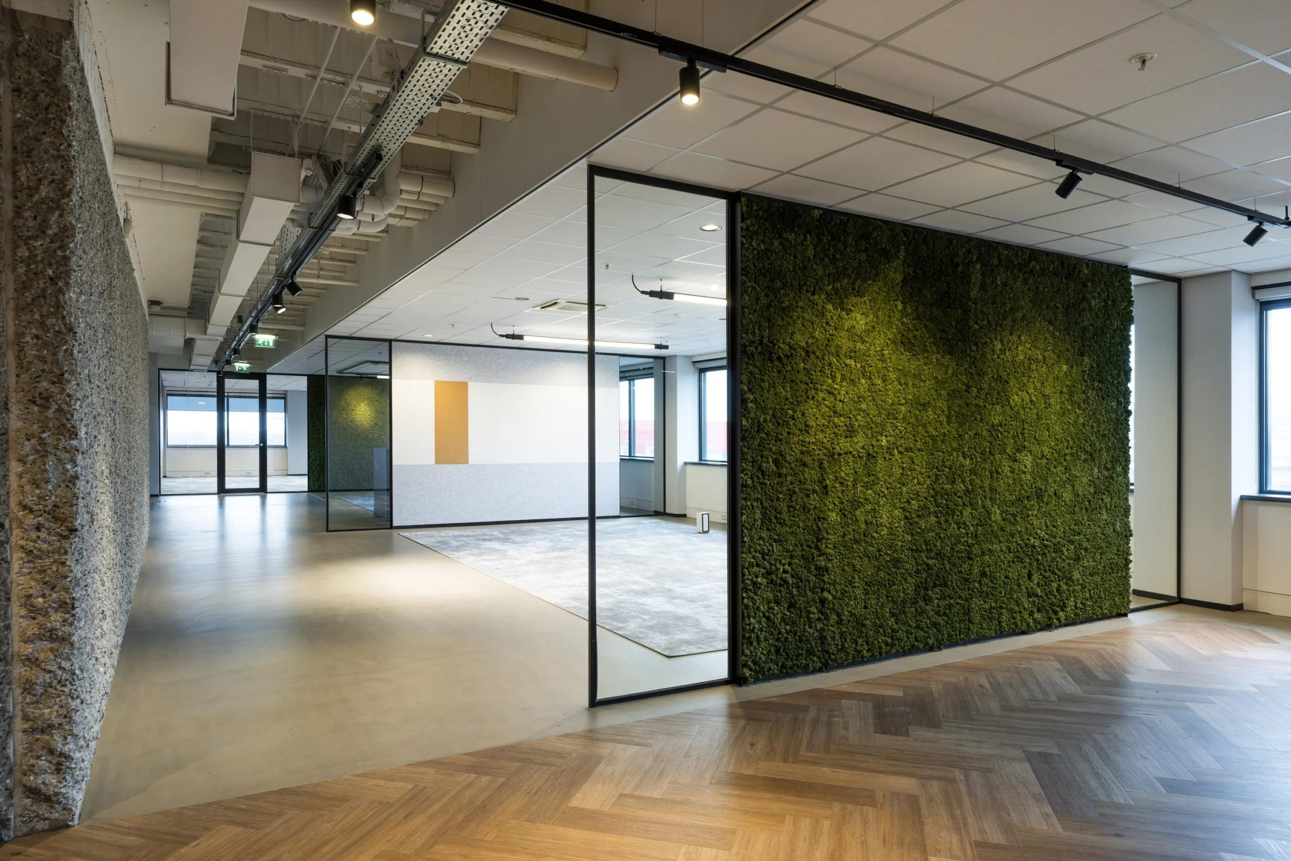 Een moderne kantoorruimte met glazen wanden en een groene moswand aan Spaklerweg.