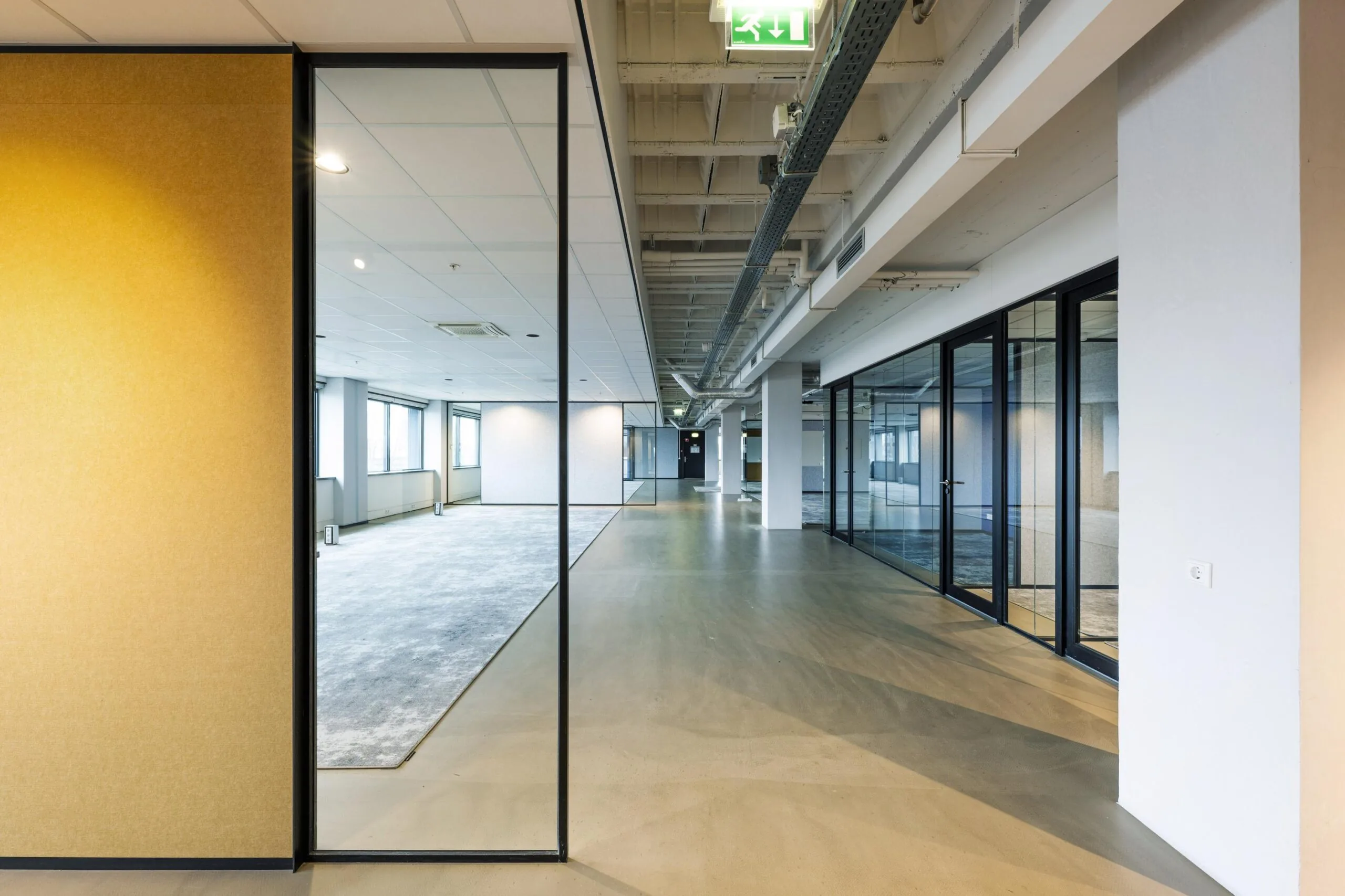 Een moderne, lege kantoorruimte met glazen wanden en een betonnen vloer aan de Spaklerweg.