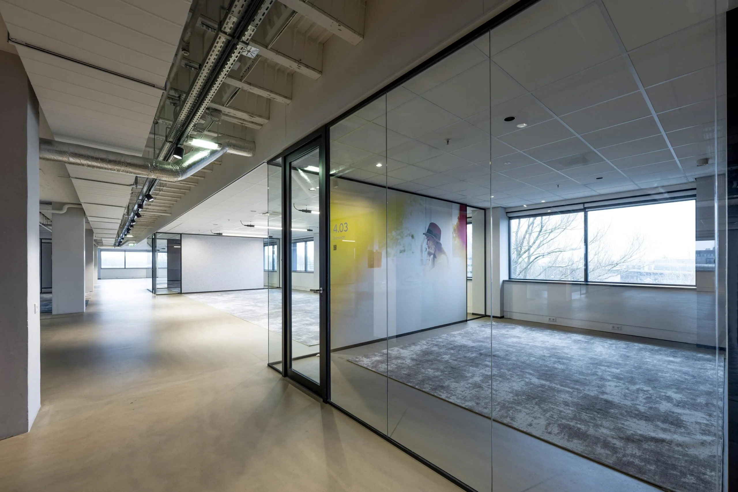Een moderne, lege kantoorruimte met glazen wanden en zicht op buiten.