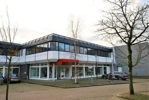 Een modern kantoorpand aan de Huis ter Heideweg met parkeerplaatsen en kale bomen ervoor.