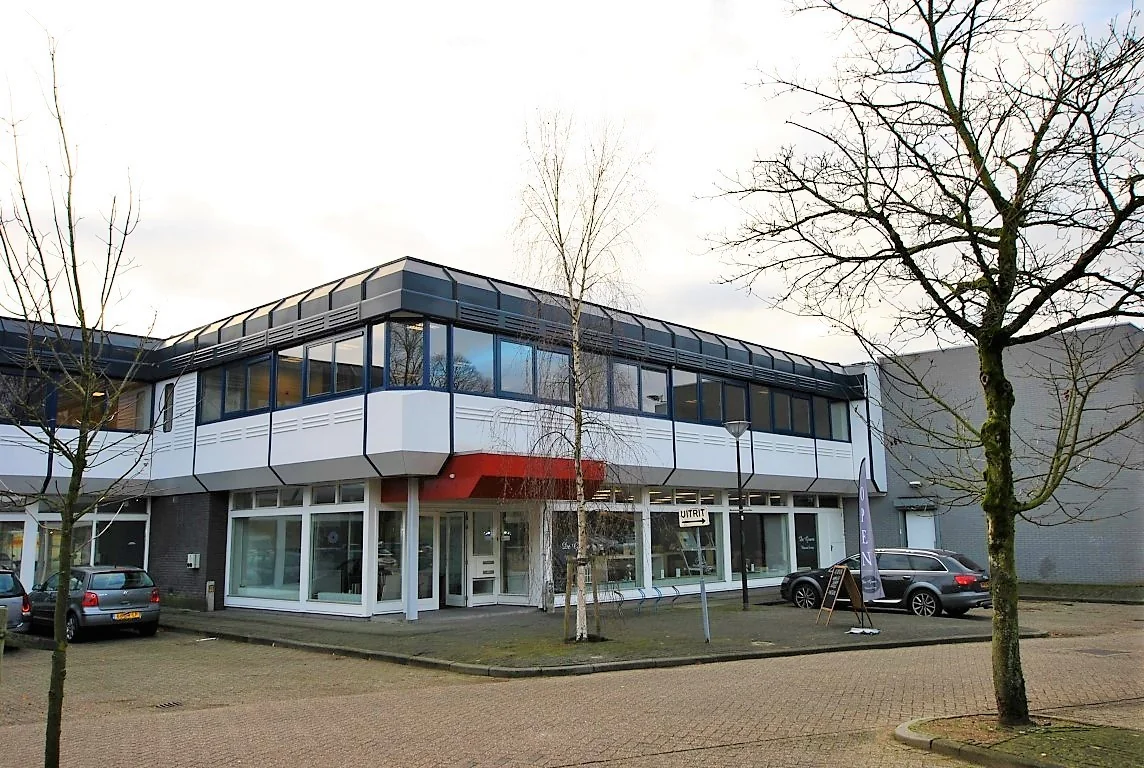 Een modern kantoorpand aan de Huis ter Heideweg met parkeerplaatsen en kale bomen ervoor.
