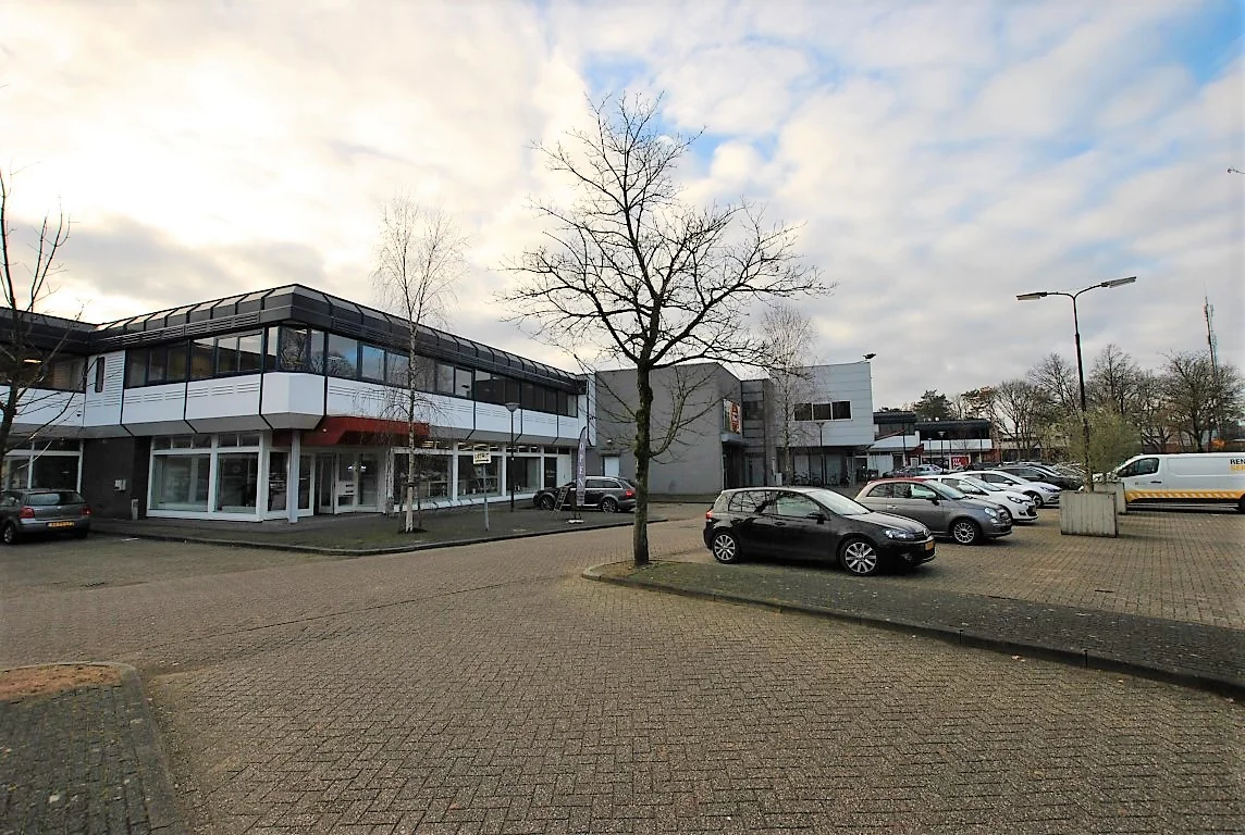 Een kantoorgebouw met parkeerplaatsen aan de Huis ter Heideweg onder een bewolkte hemel.
