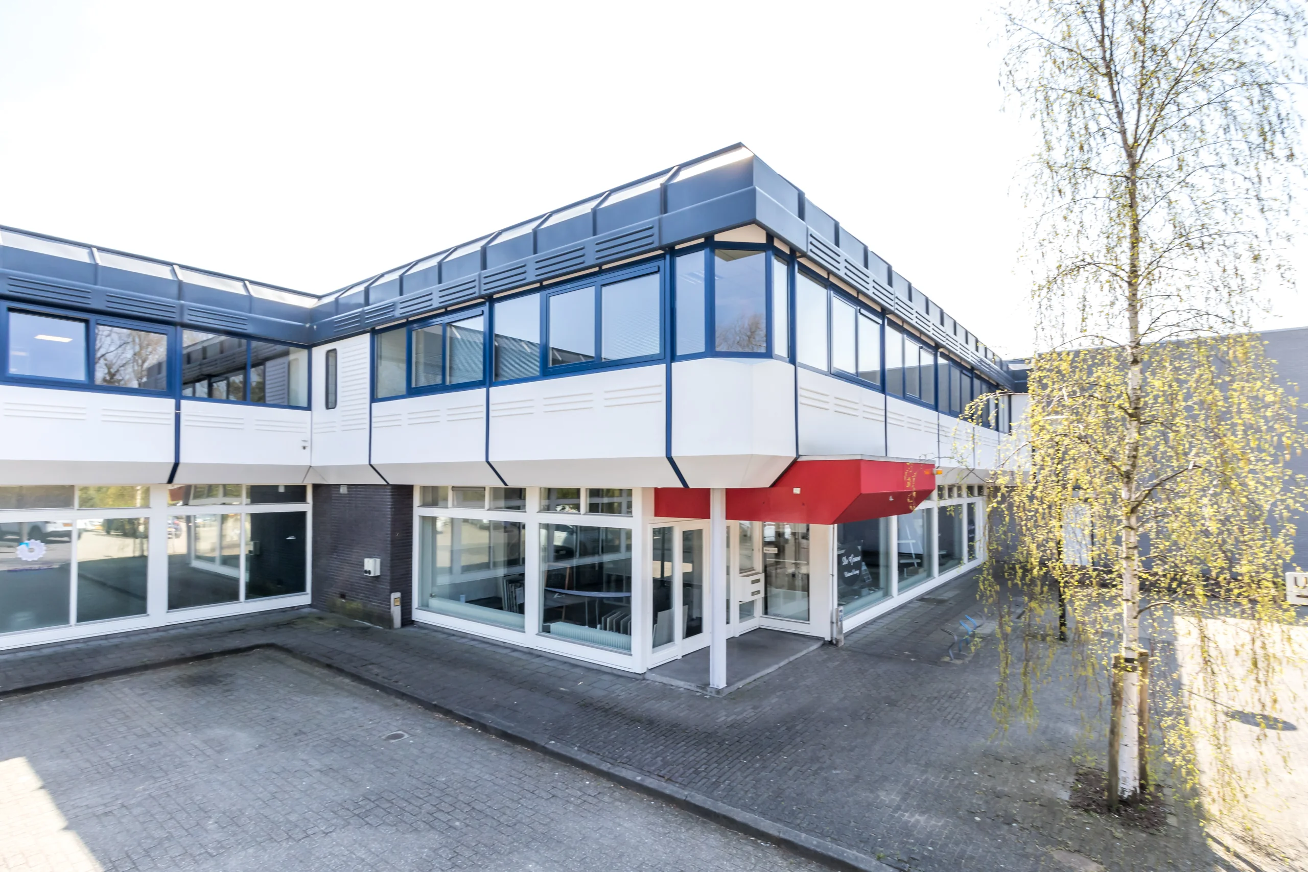 Een modern bedrijfsgebouw met glazen gevel en overhangend dak aan de Huis ter Heideweg.