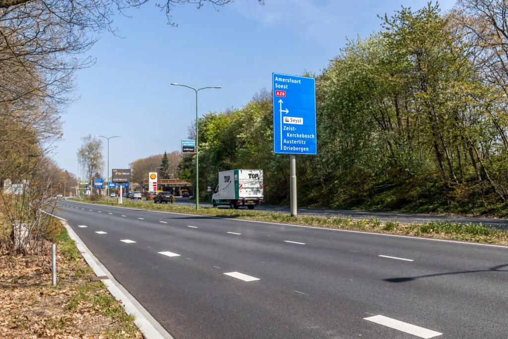 Een rustige weg met een verkeersbord richting Amersfoort en Soest nabij een Shell-tankstation.