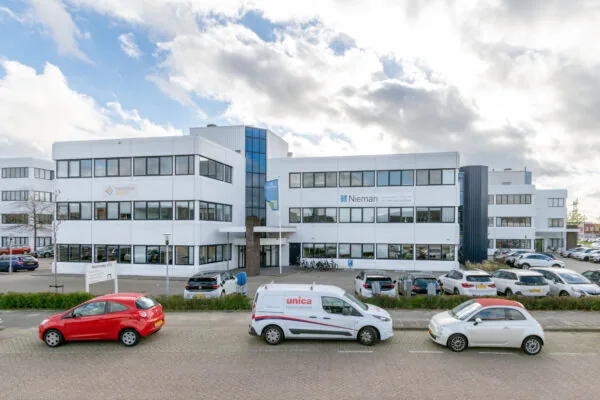 Vooraanzicht van een kantoorgebouw aan de Atoomweg met bedrijfsvoertuigen geparkeerd op de voorgrond.