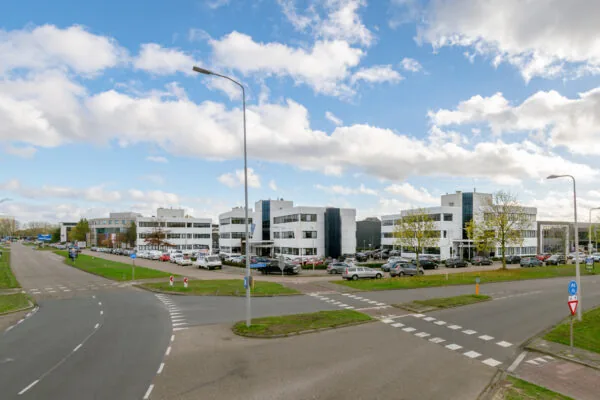 Zakelijke gebouwen aan de Atoomweg met parkeerplaatsen aan een kruispunt onder een blauwe lucht.
