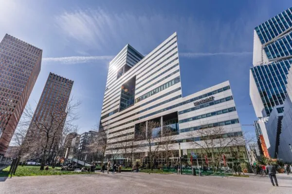 Moderne hoge gebouwen en een plein met mensen op het Gustav Mahlerplein op een zonnige dag.