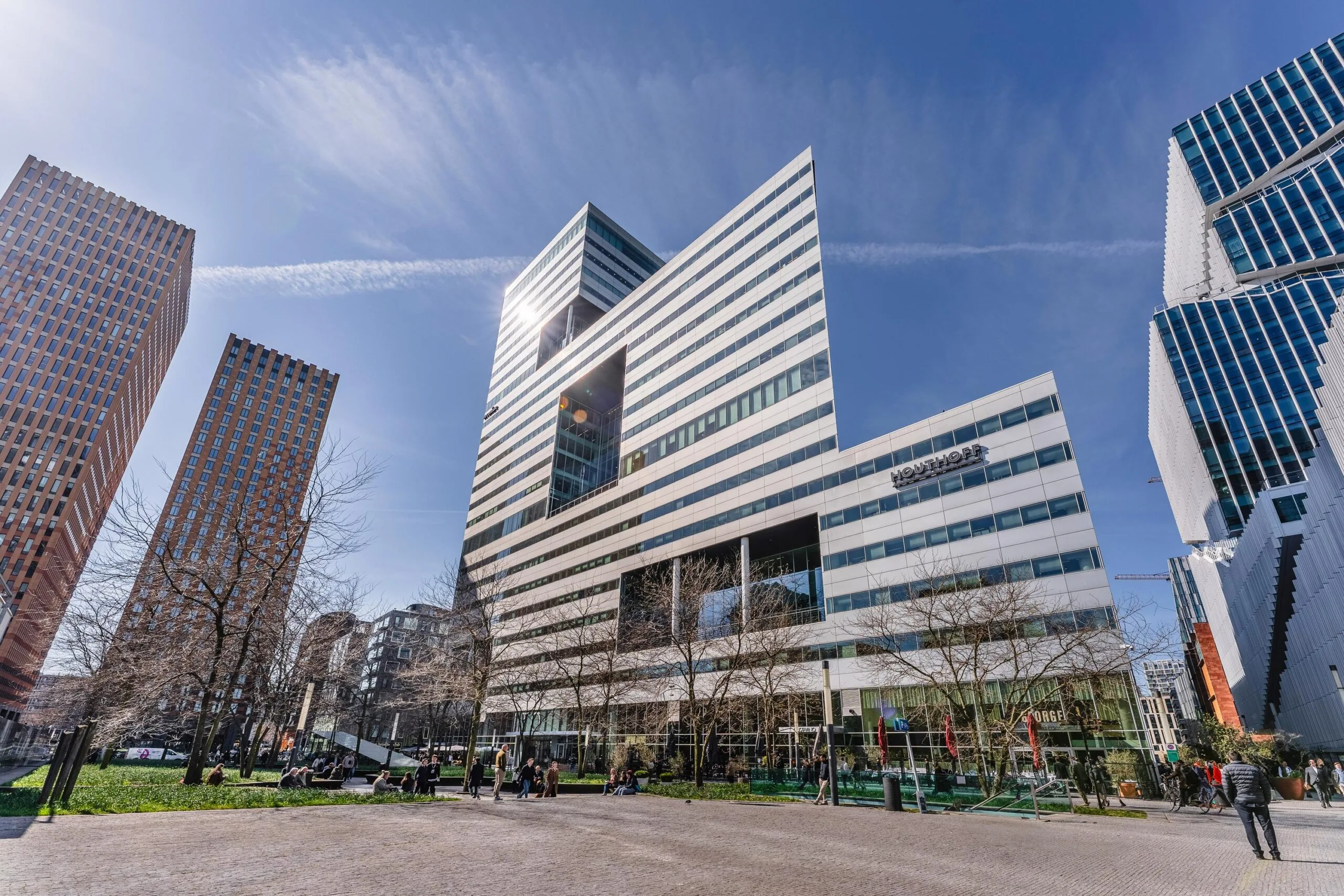 Moderne hoge gebouwen en een plein met mensen op het Gustav Mahlerplein op een zonnige dag.