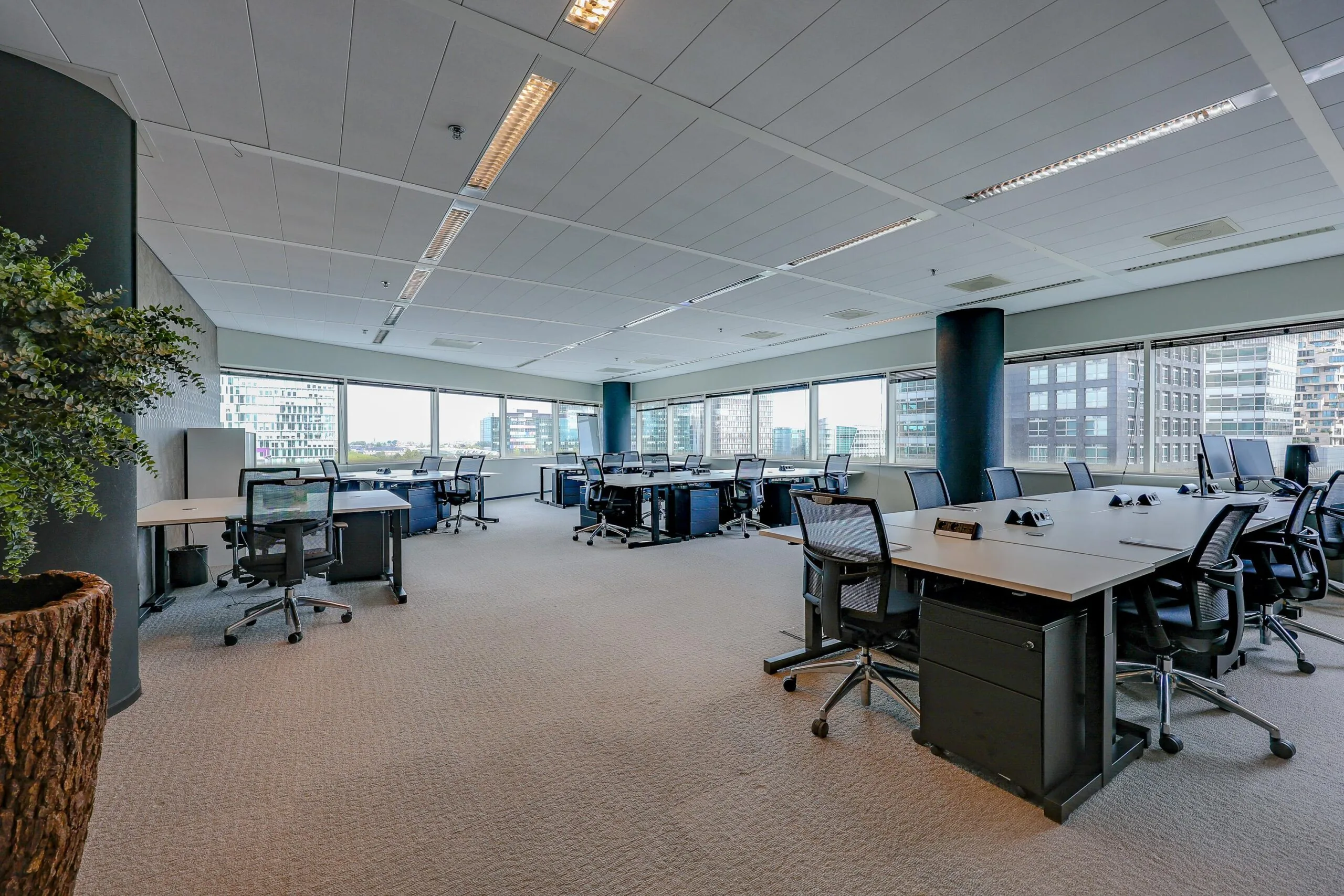 Een modern en ruim kantoor met meerdere bureaus en stoelen op het Gustav Mahlerplein.