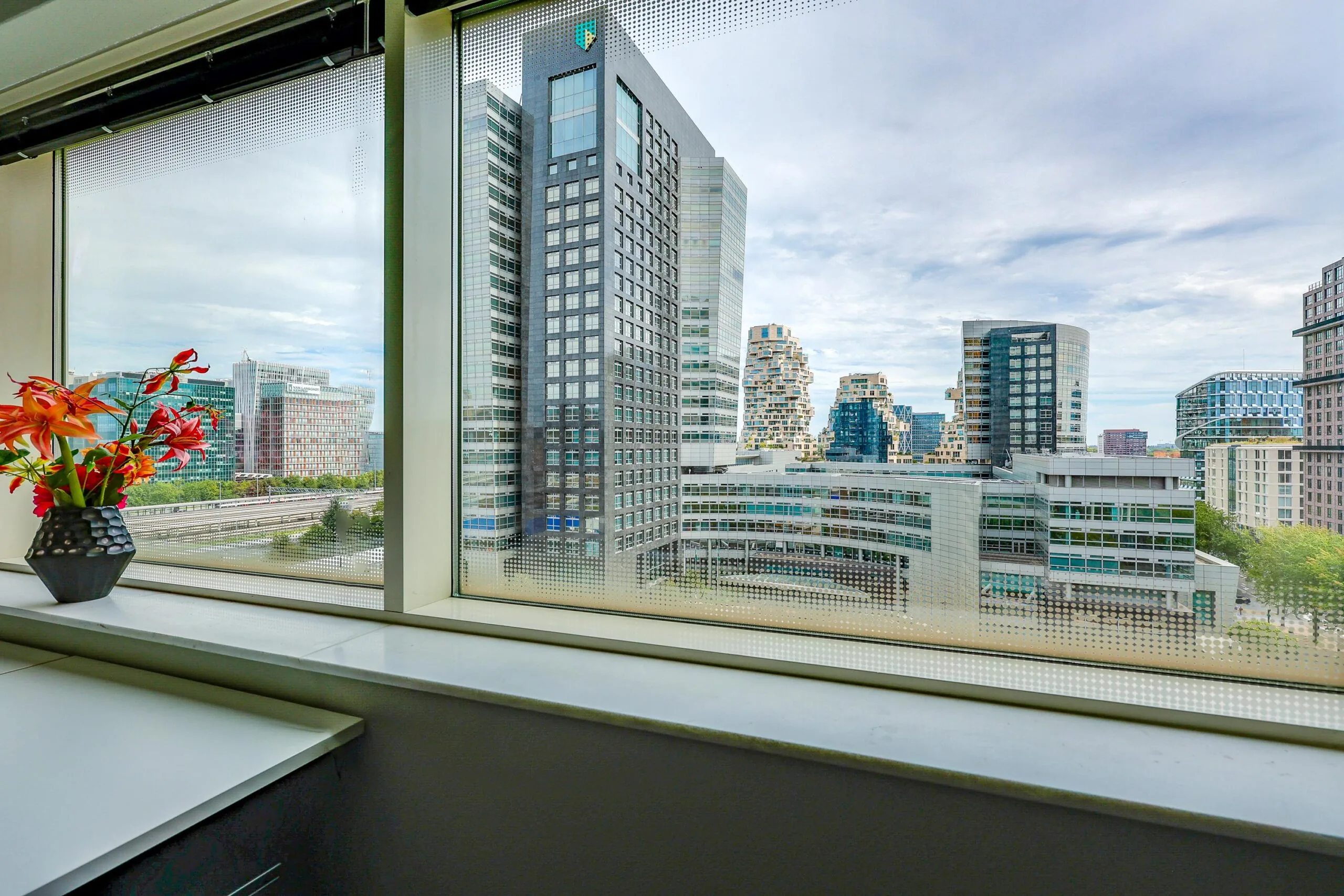 Uitzicht vanuit een venster op moderne gebouwen aan het Gustav Mahlerplein.
