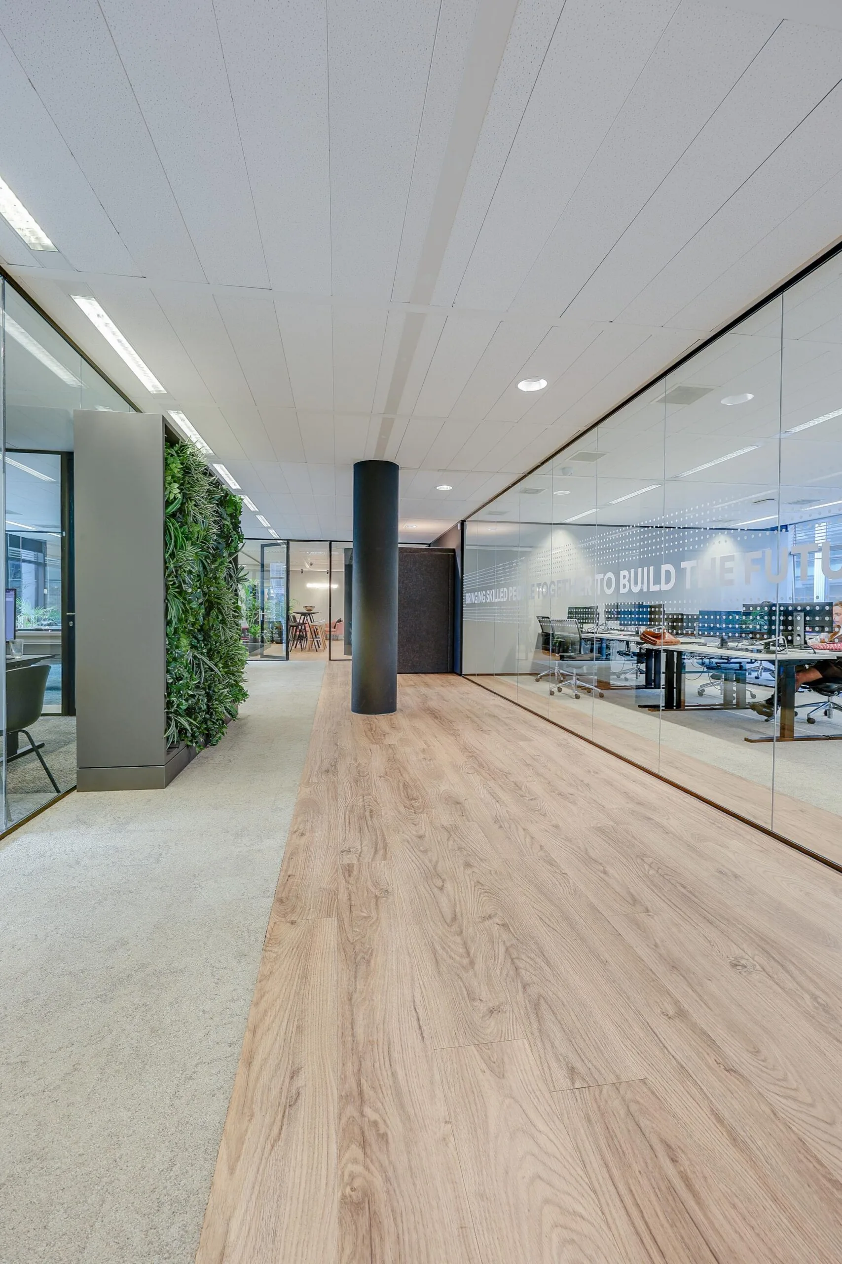 Een moderne kantoorruimte met glazen wanden en een groene plantenwand op de Gustav Mahlerlaan.