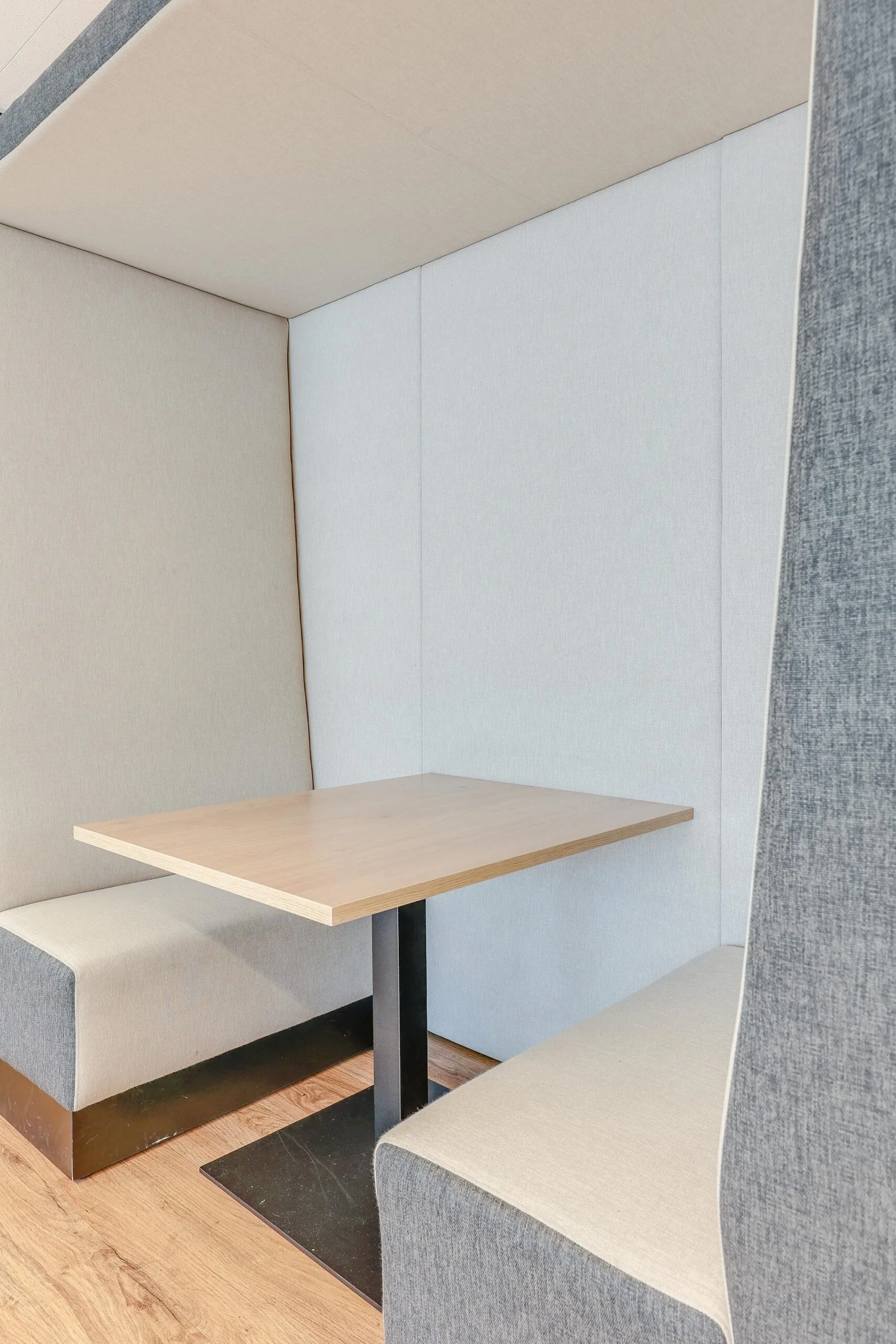 Een moderne zithoek met een houten tafel en beklede banken in een kantooromgeving aan de Gustav Mahlerlaan.