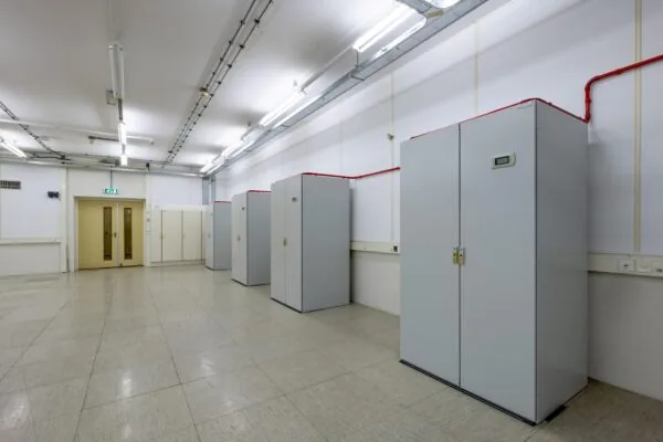 Een lege kamer met meerdere grijze kasten in een rij langs de muur.