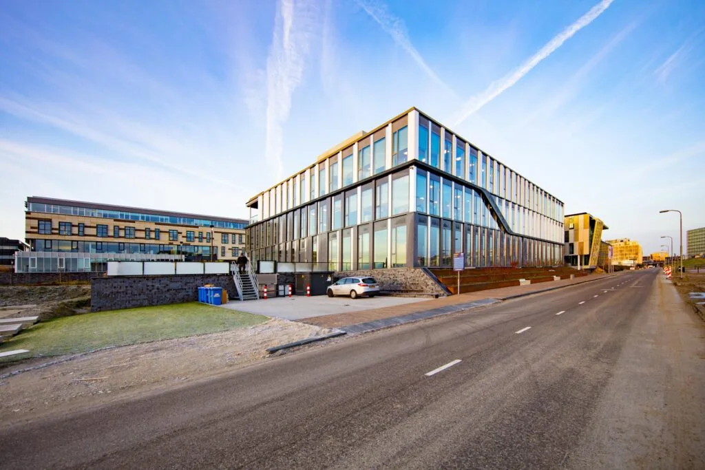 Een modern kantoorgebouw aan een rustige weg bij zonsopgang.