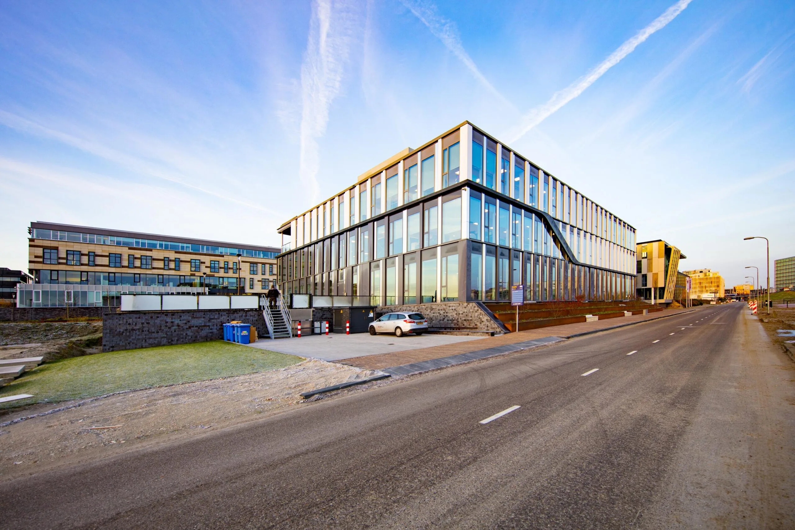 Een modern kantoorgebouw aan een rustige weg bij zonsopgang.