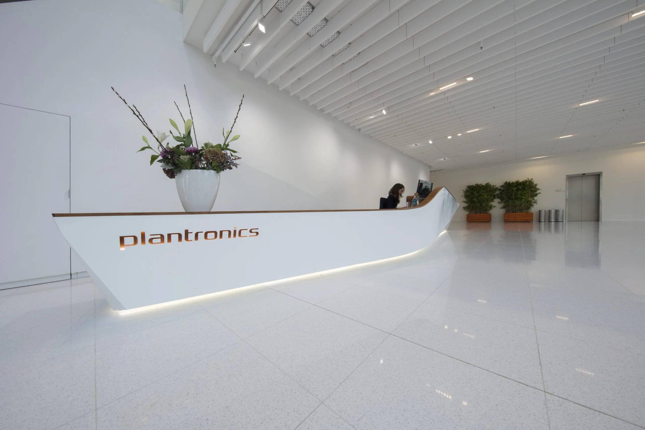 Een moderne receptiebalie in een strak kantoor met het logo van Plantronics.