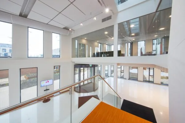 Interieur van een modern kantoorgebouw met glazen balustrades en grote ramen.