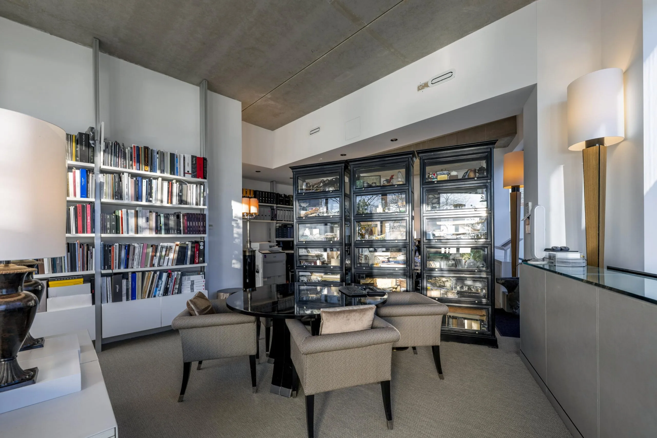 Een moderne vergaderruimte met een glazen tafel, comfortabele stoelen en boekenplanken.