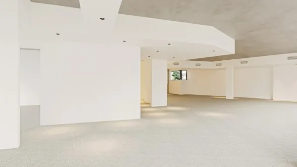 Een grote, lege ruimte met witte muren en plafonds, verlicht door inbouwlampen.